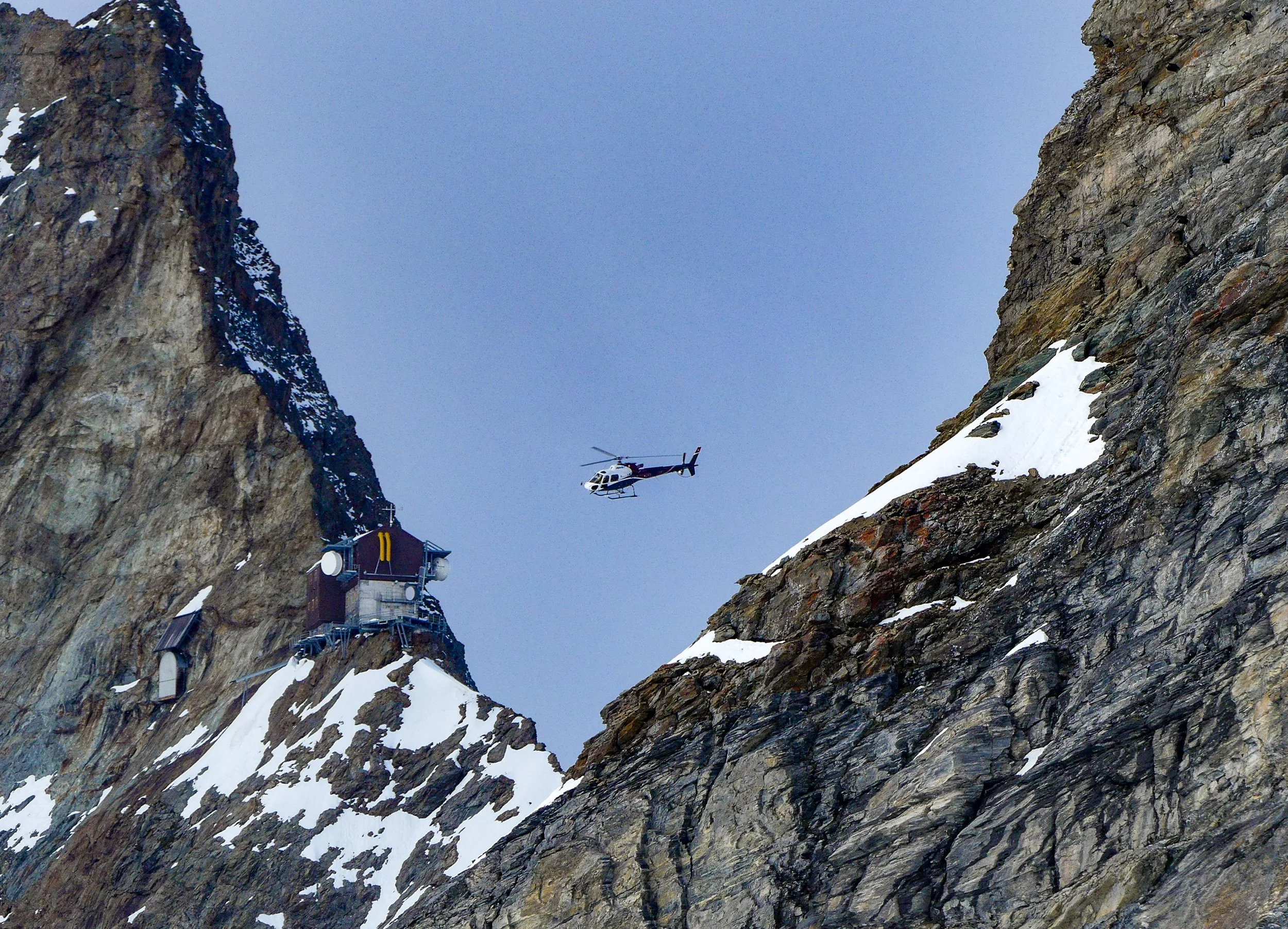 Helicopter inbetween mountain peaks on the Jungfrau summit, Switzerland 