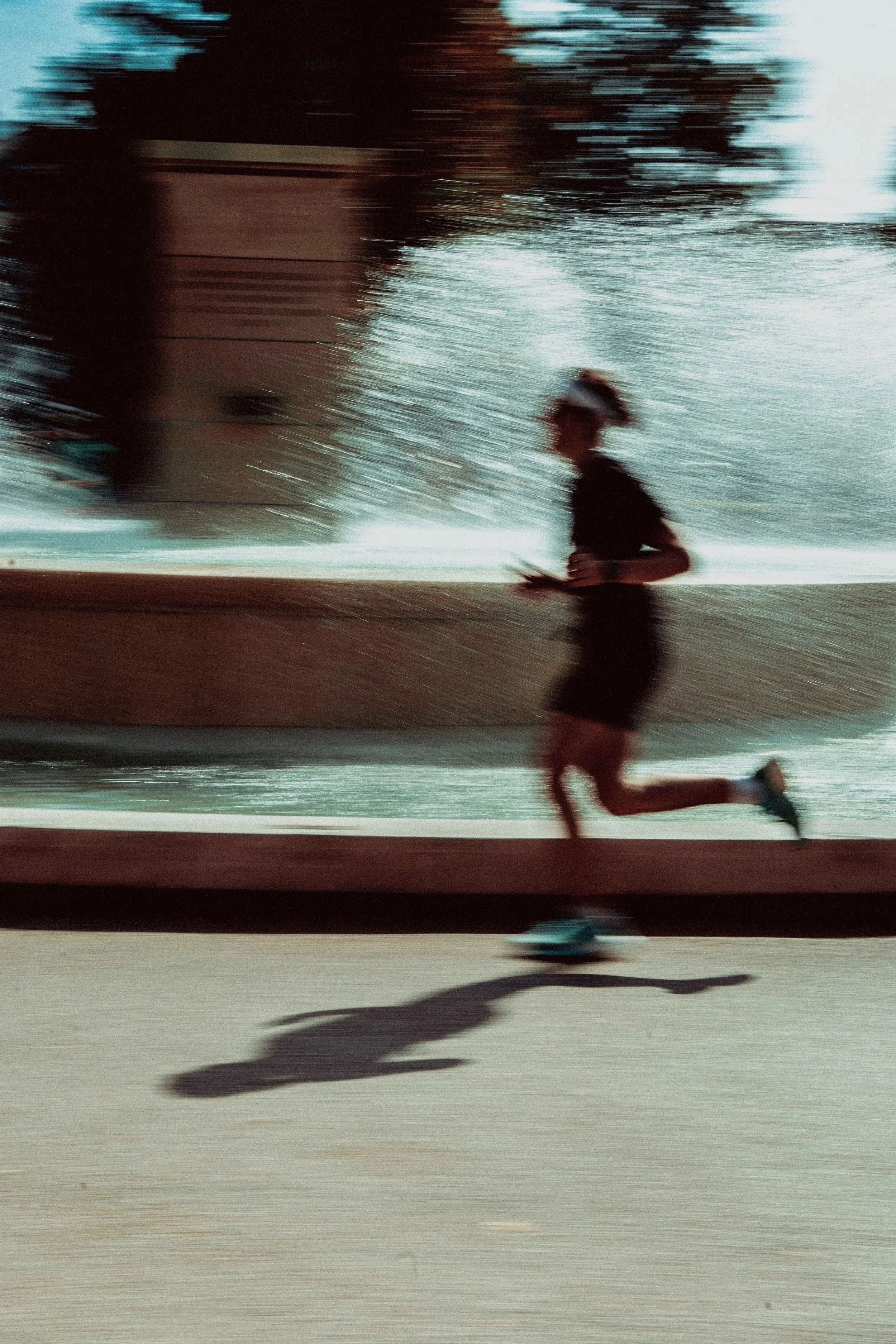 Une personne court vite en portant une tenue de sport, avec un casque ou serre-tête, le tout en mouvement flou, probablement lors d'une session de jogging ou de course à pied.