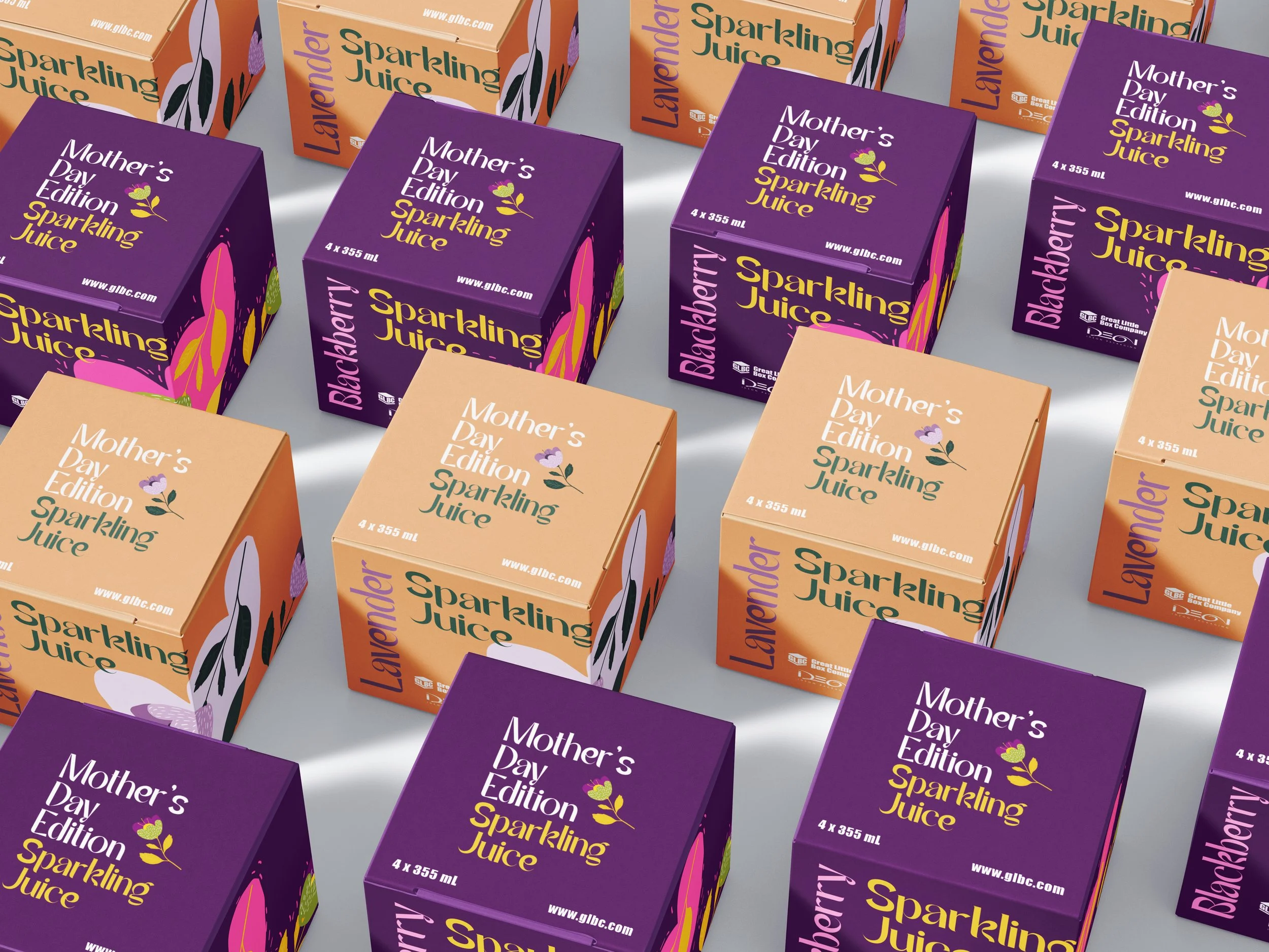 Multiple colorful boxes of sparkling juice arranged in a pattern, with purple and orange packaging. The purple boxes are labeled "Mother's Day Edition Sparkling Juice" with a small flower illustration, and the orange boxes are labeled "Lavender Sparkling Juice."
