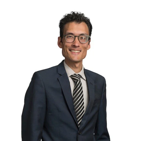 Tristan Carter who is a professional coach wearing a blue suit and wearing glasses on a white background