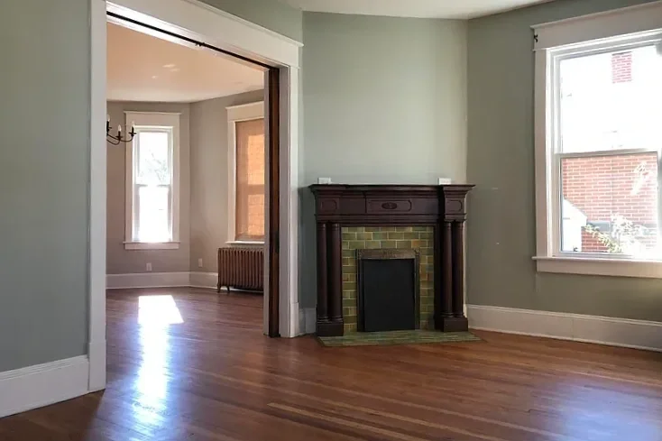 Beautifully painted living room with hardwood floors, fireplace with dark wood mantel, and large windows with natural light.