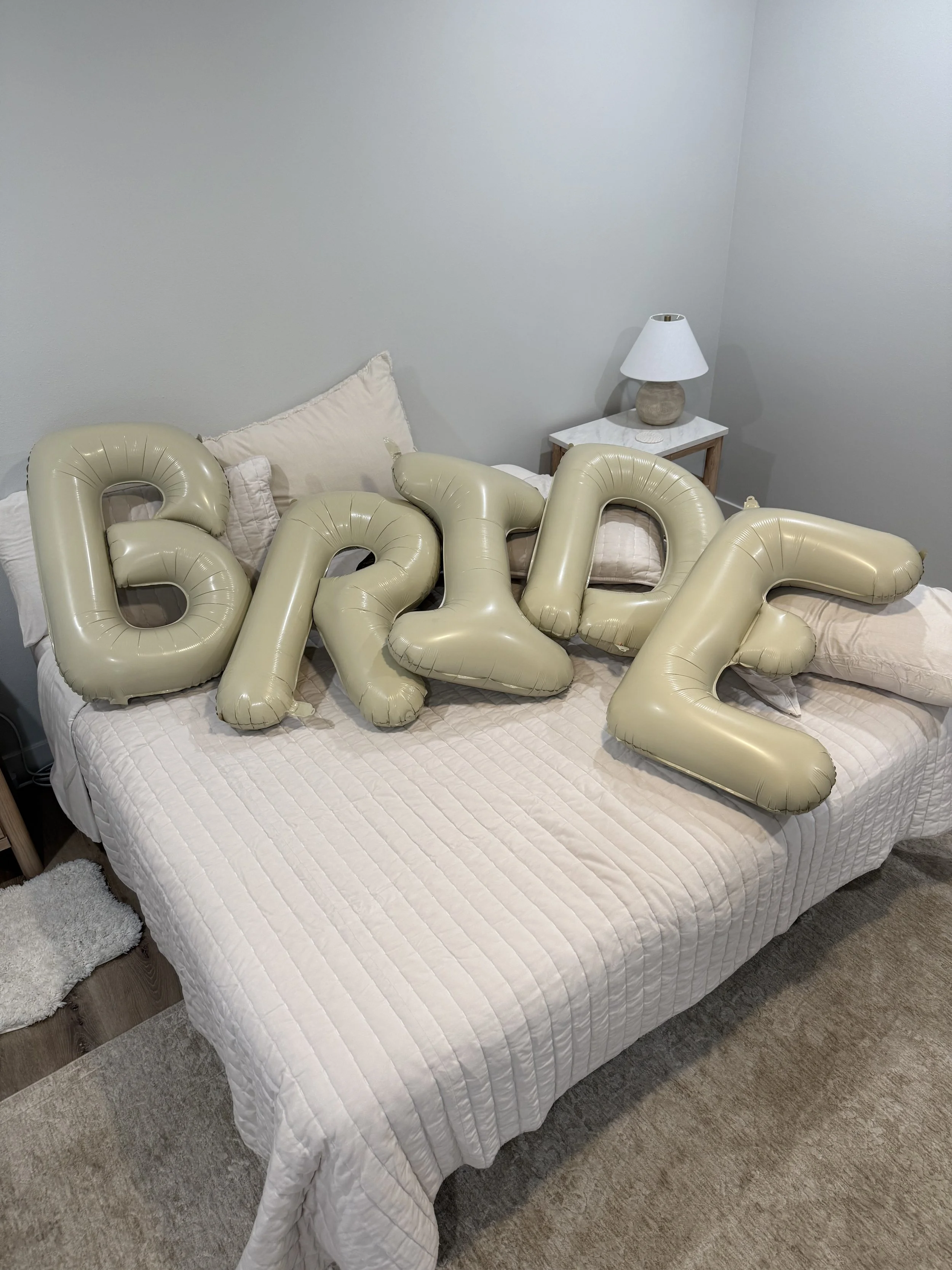 Gold balloon letters spelling 'GRAD' arranged on a bed in a bedroom.
