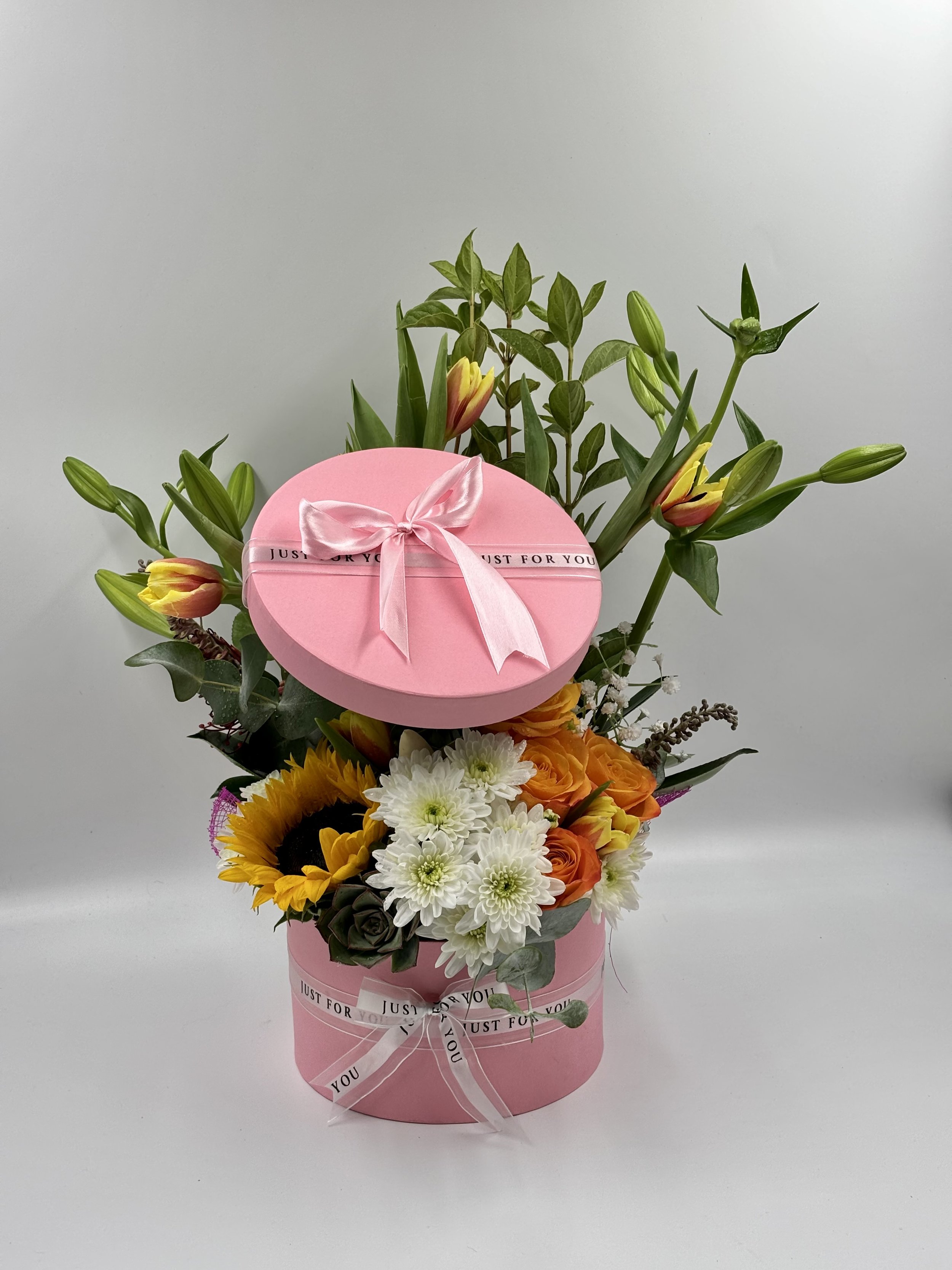 BESPOKE HAT BOX 
Elegant Pink Hatbox Bouquet featuring sunflowers, roses, lilies, and chrysanthemums with a satin ribbon, handcrafted by The Bouquet Bar Adelaide. (Click on Image to Enquire.)