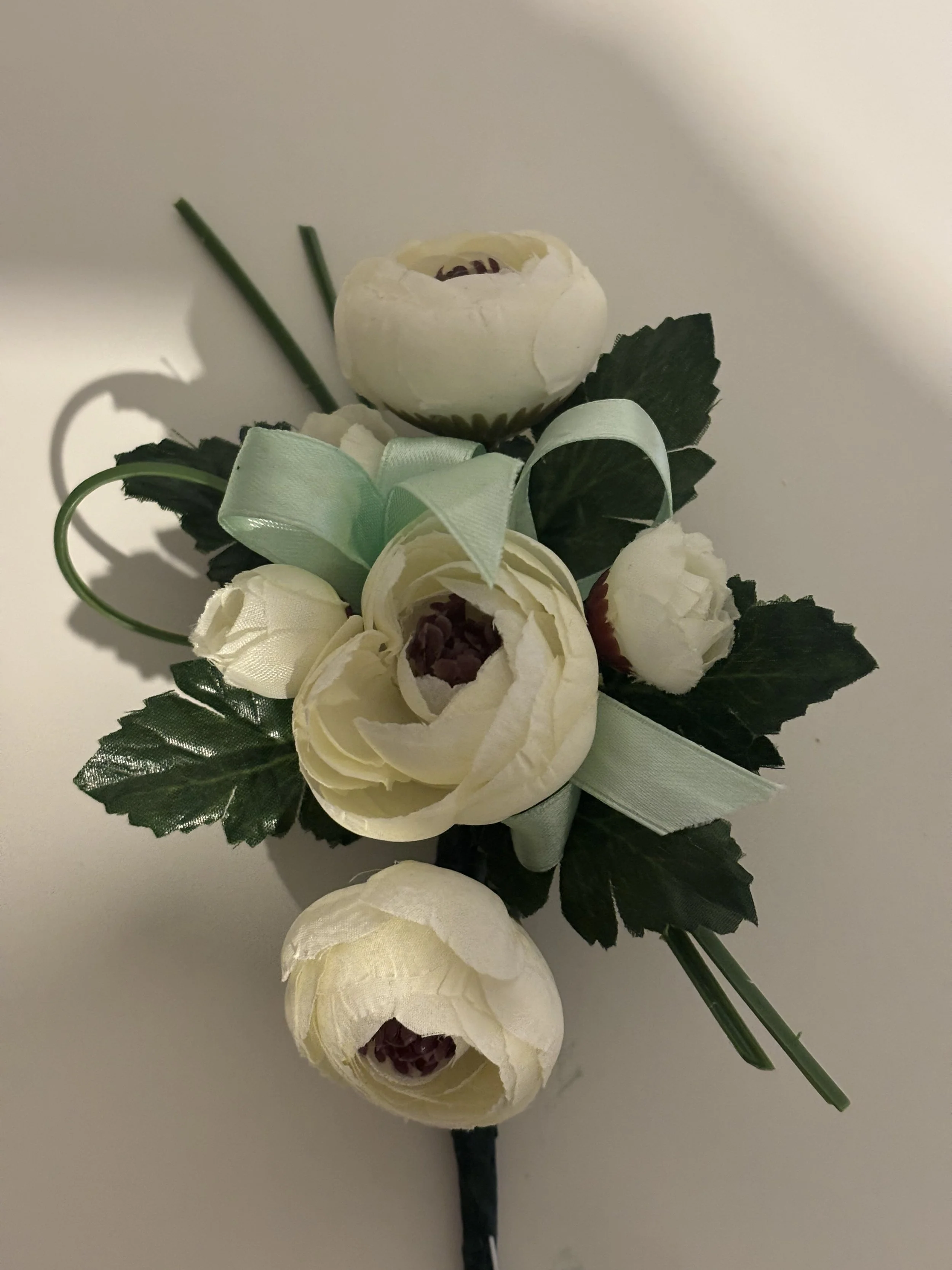 ELEGANT CREAM RANUNCULUS CORSAGE
A Timeless Wrist Corsage featuring a delicate cream ranunculus bloom, complemented by soft green foliage. Hand-tied with a refined satin ribbon, this piece is perfect for formal events, weddings, or school formals — u