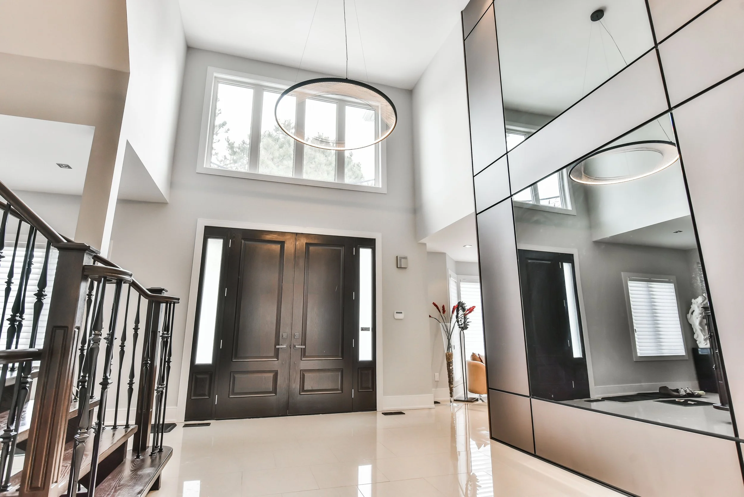 Double front doors with high windows and contemporary chandelier in modern entryway.