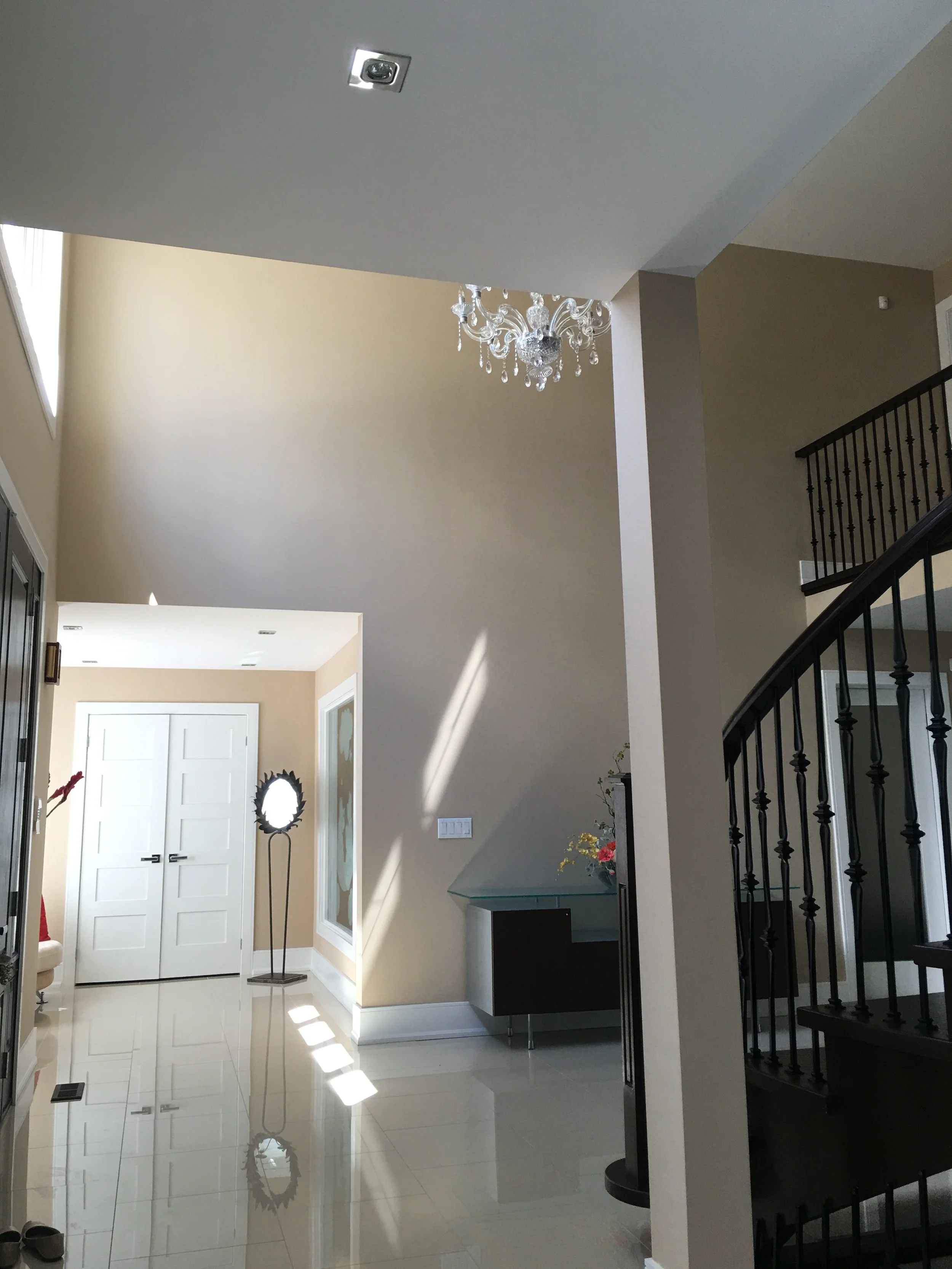 Open entryway with chandelier and neutral tones before design update
