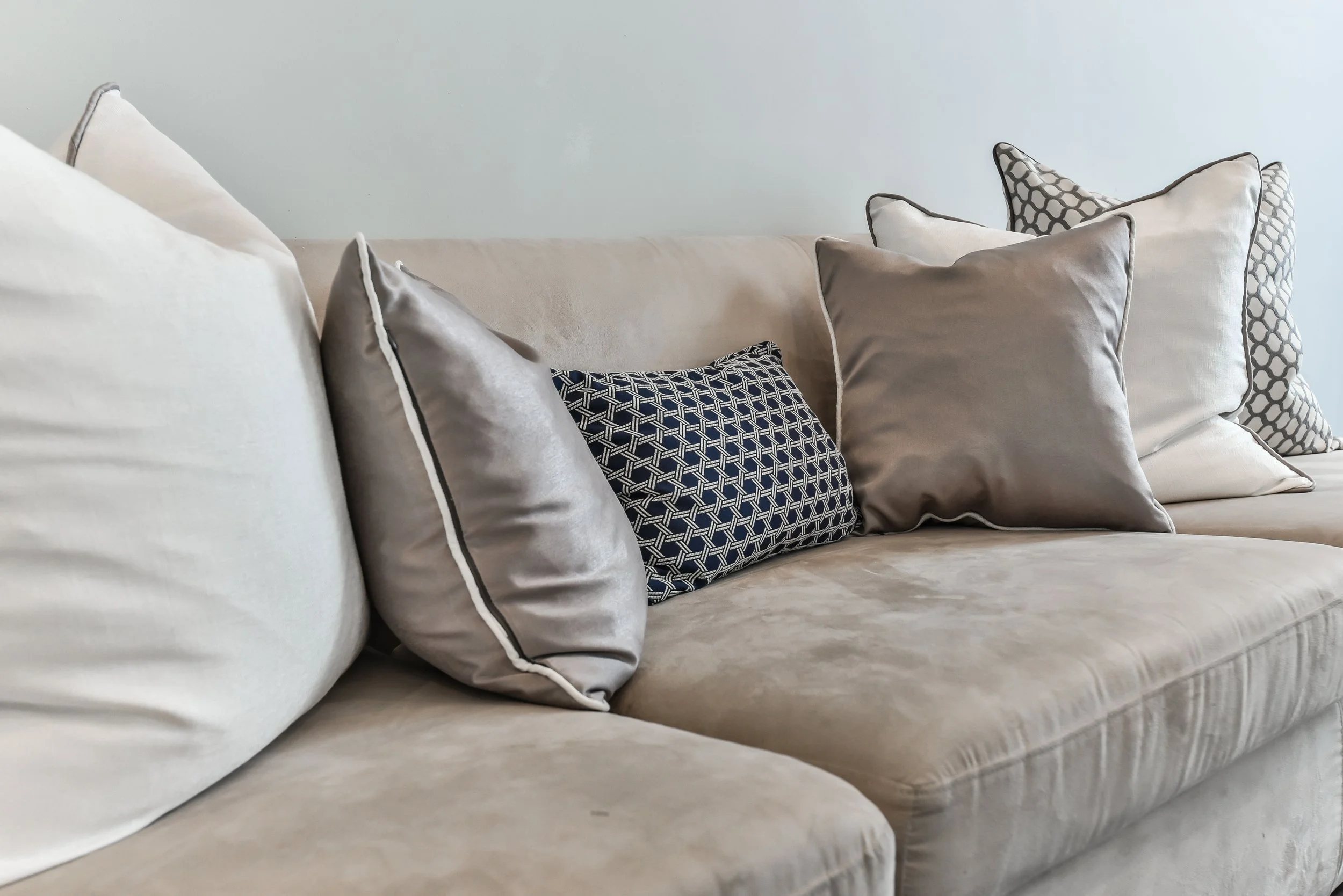 Close-up of beige sofa with designer accent pillows in luxury living space.