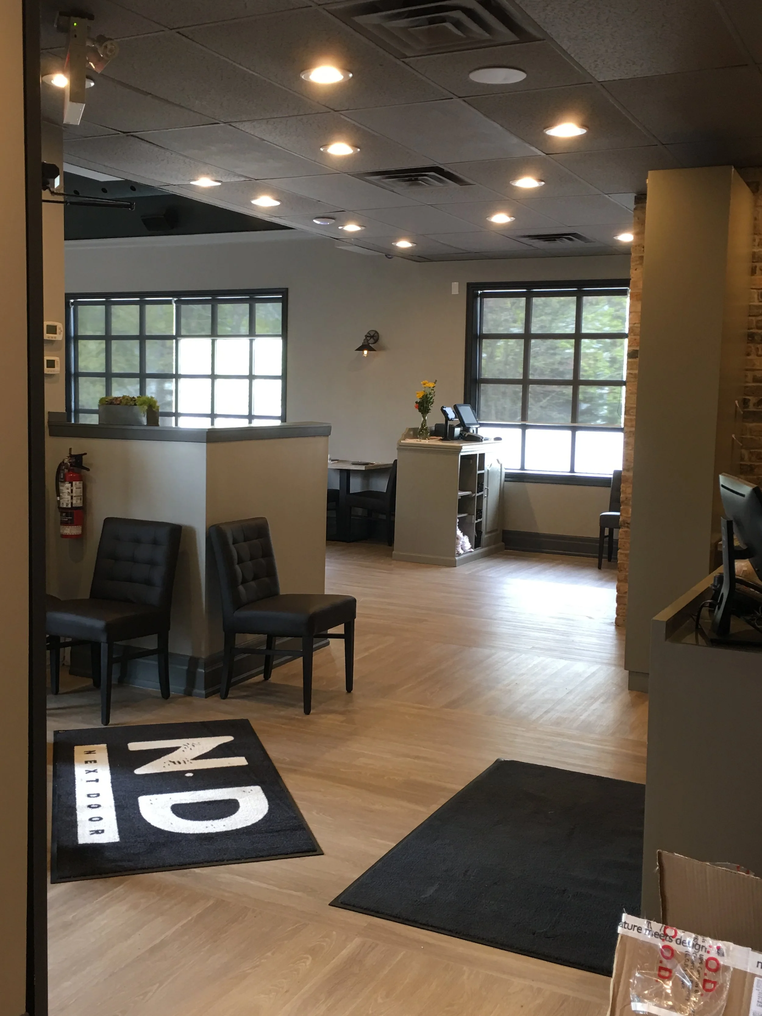 Cozy lounge space at Next Door Restaurant with tufted seating, wide grid windows, and soft ambient lighting.