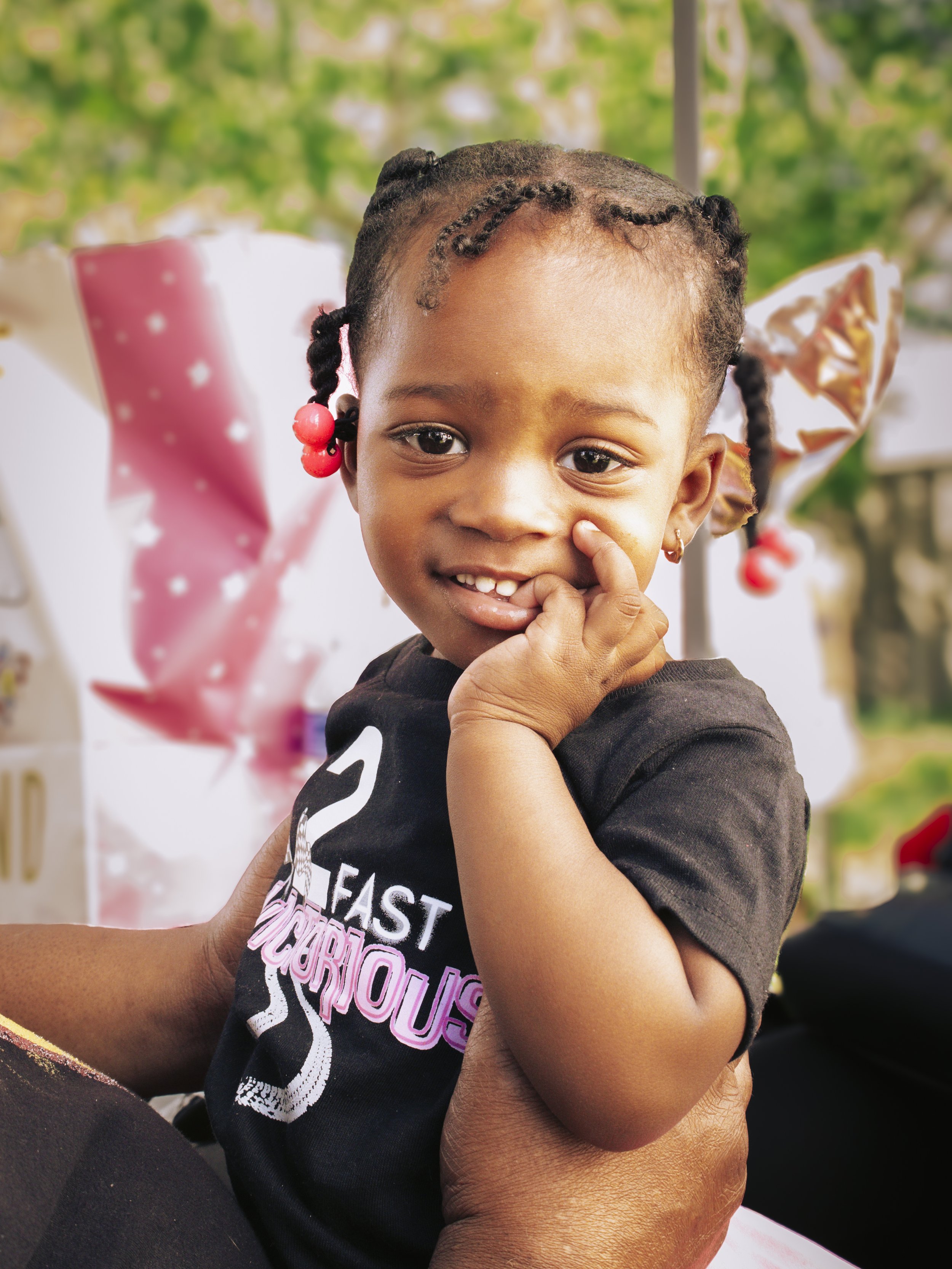 Smiling toddler wearing a black shirt with a hand touching their face. Image taken by Maryland family photographer.