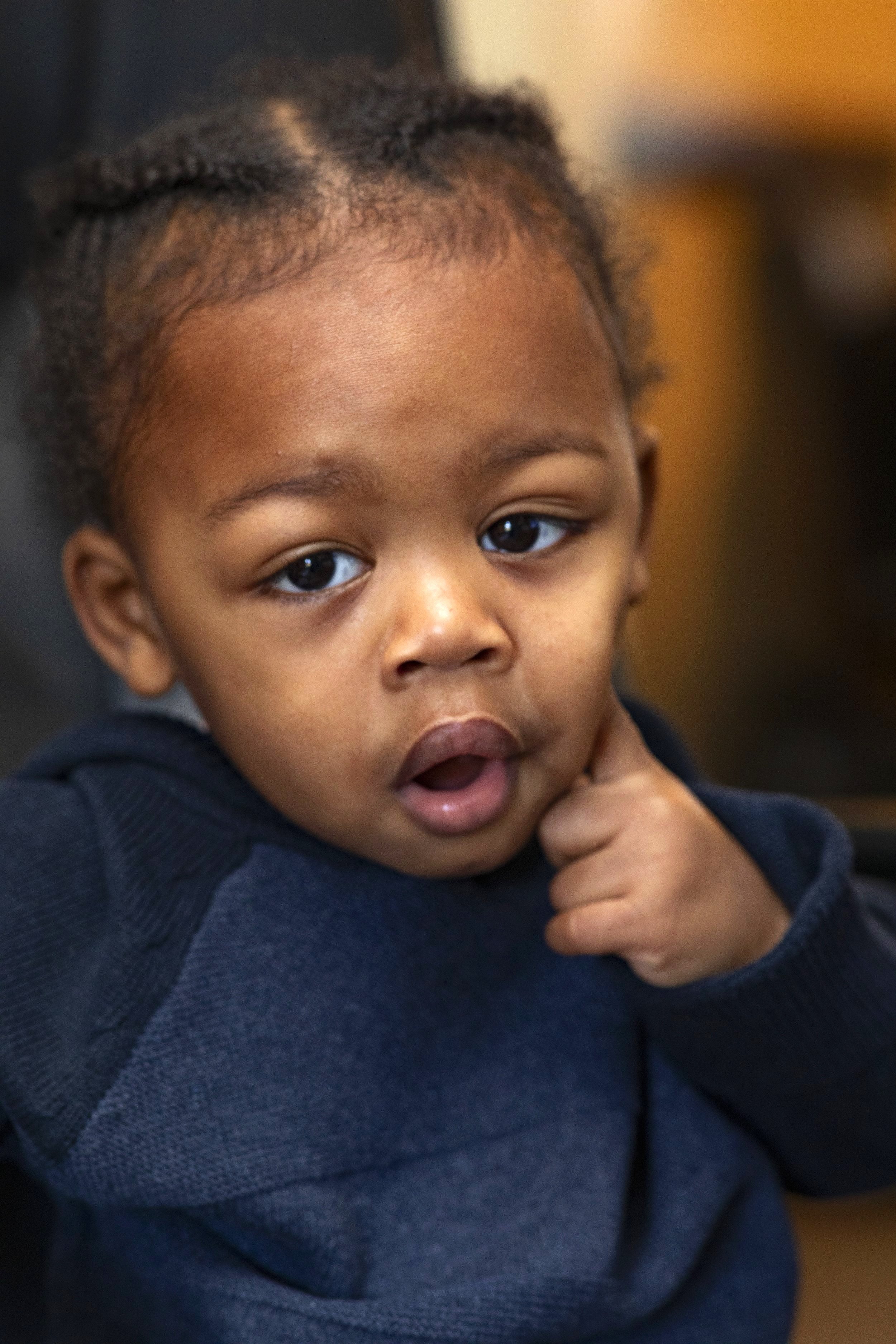 Close-up of a young child with braided hair in a blue sweater, taken by Maryland family photographer.