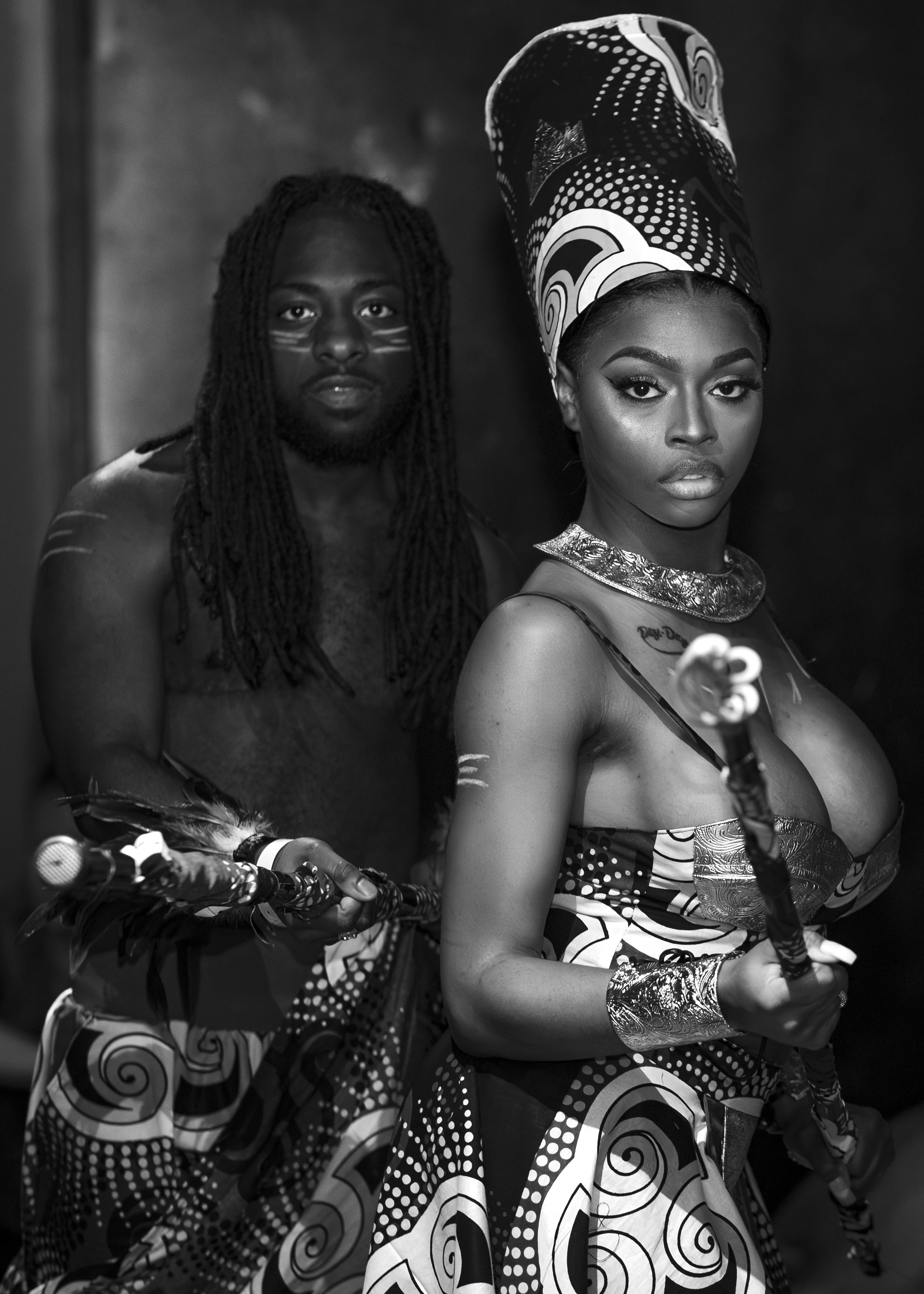 Two people dressed in traditional African attire, holding staffs, with intricate patterns and headwear. Image by Maryland event photographer.