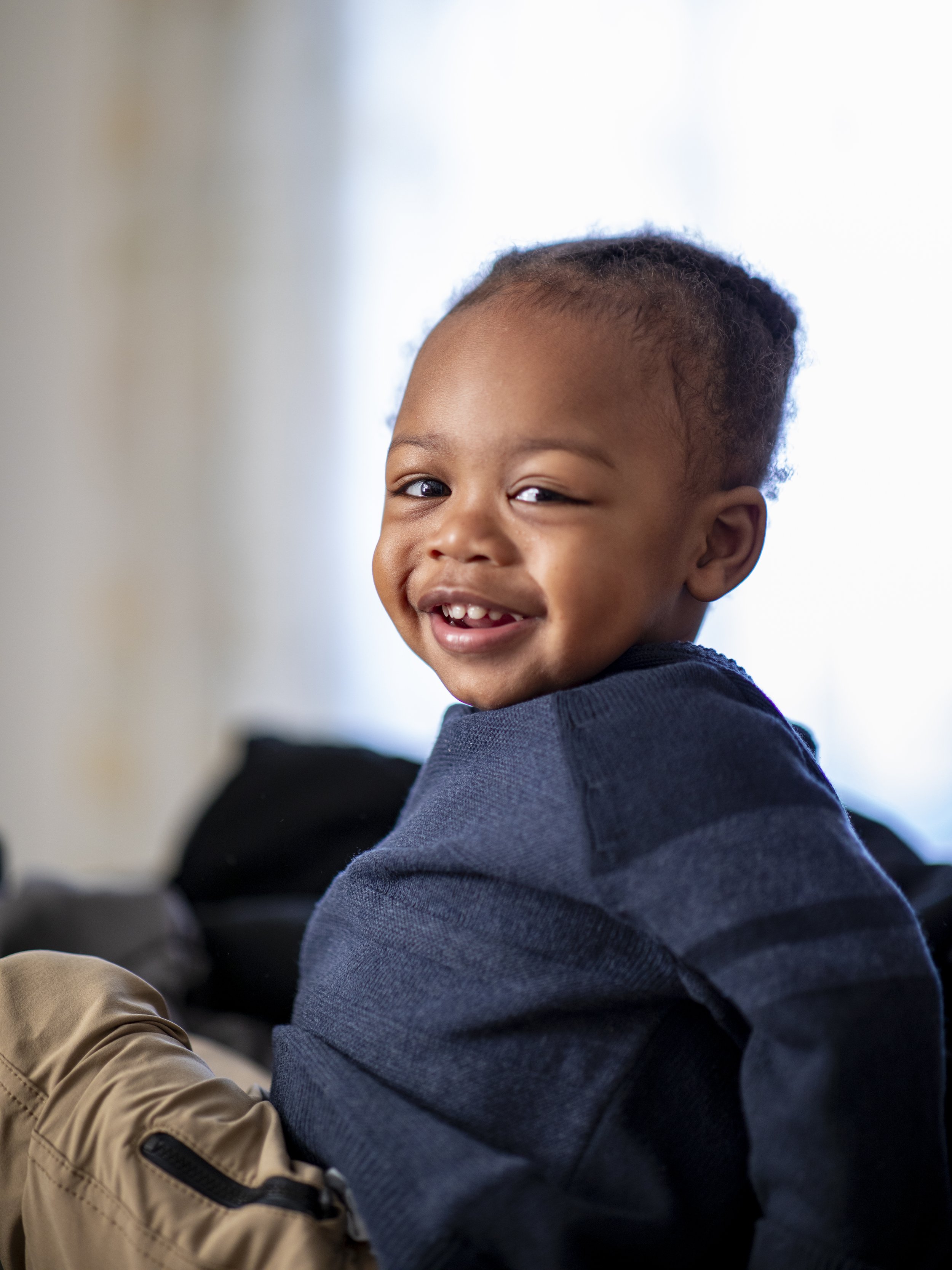 Smiling child in a navy sweater and beige pants. Image by Maryland family photographer.