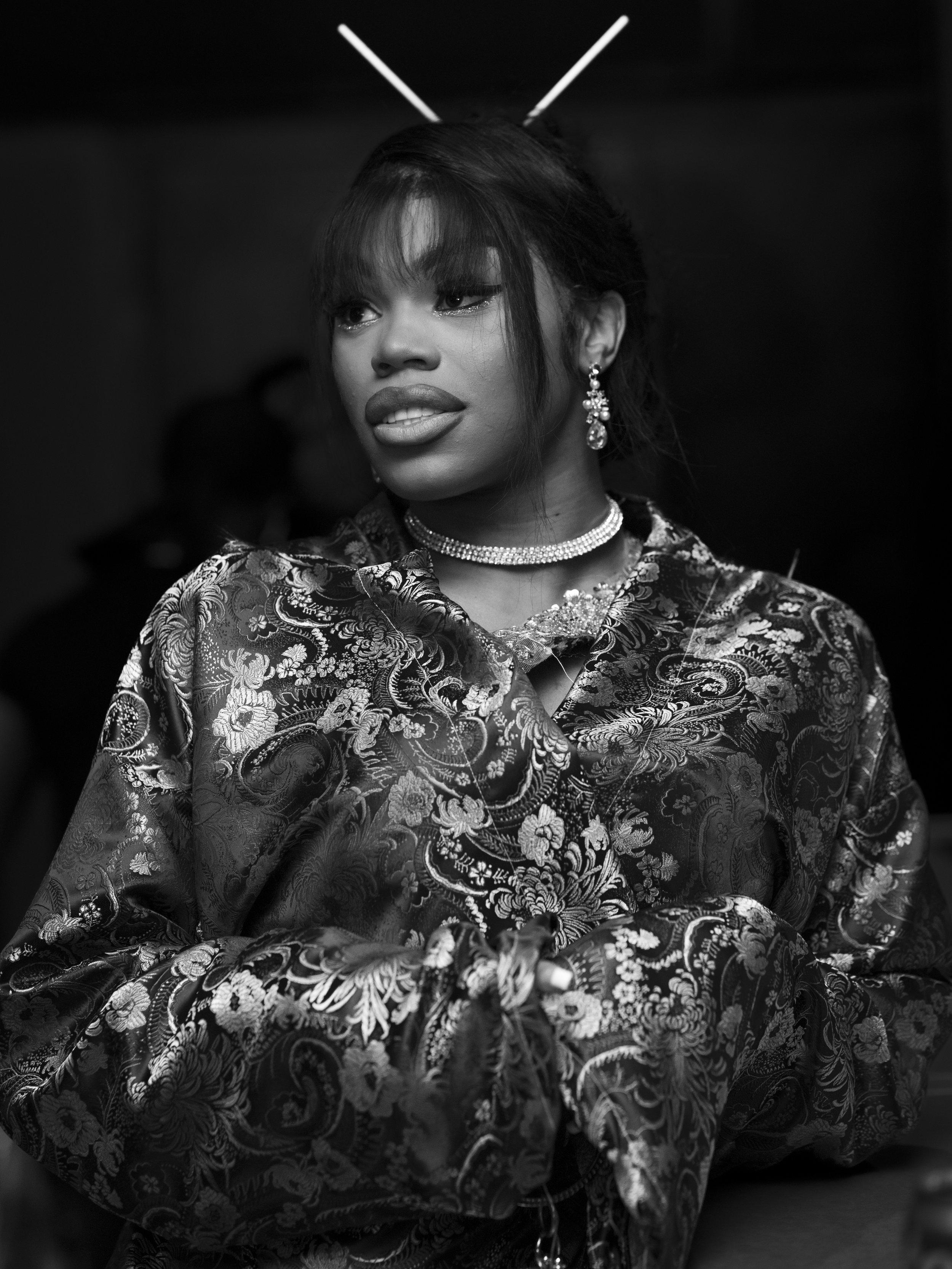 Black and white portrait by Washington, D.C. photographer, of a woman in a patterned, silk robe with chopsticks in her hair, wearing jewelry, looking to the side.