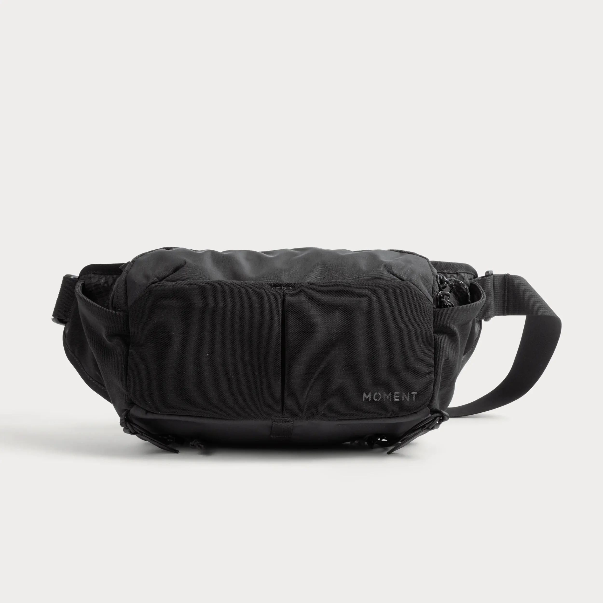 Black backpack with the word 'MOMENT' written in gray, placed on a white background.