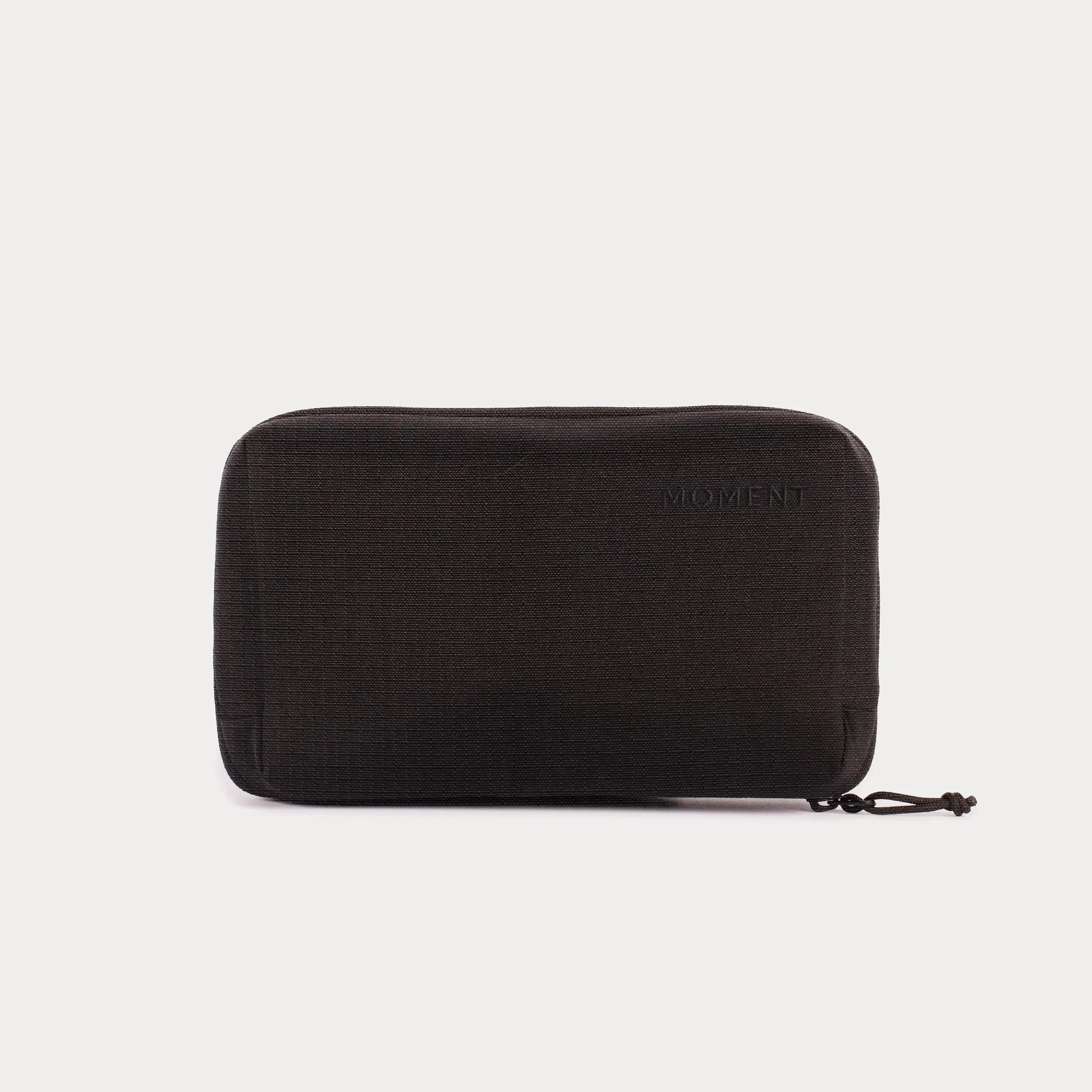 A black foam yoga block with textured surface and a small loop attached on the side, placed against a plain white background.