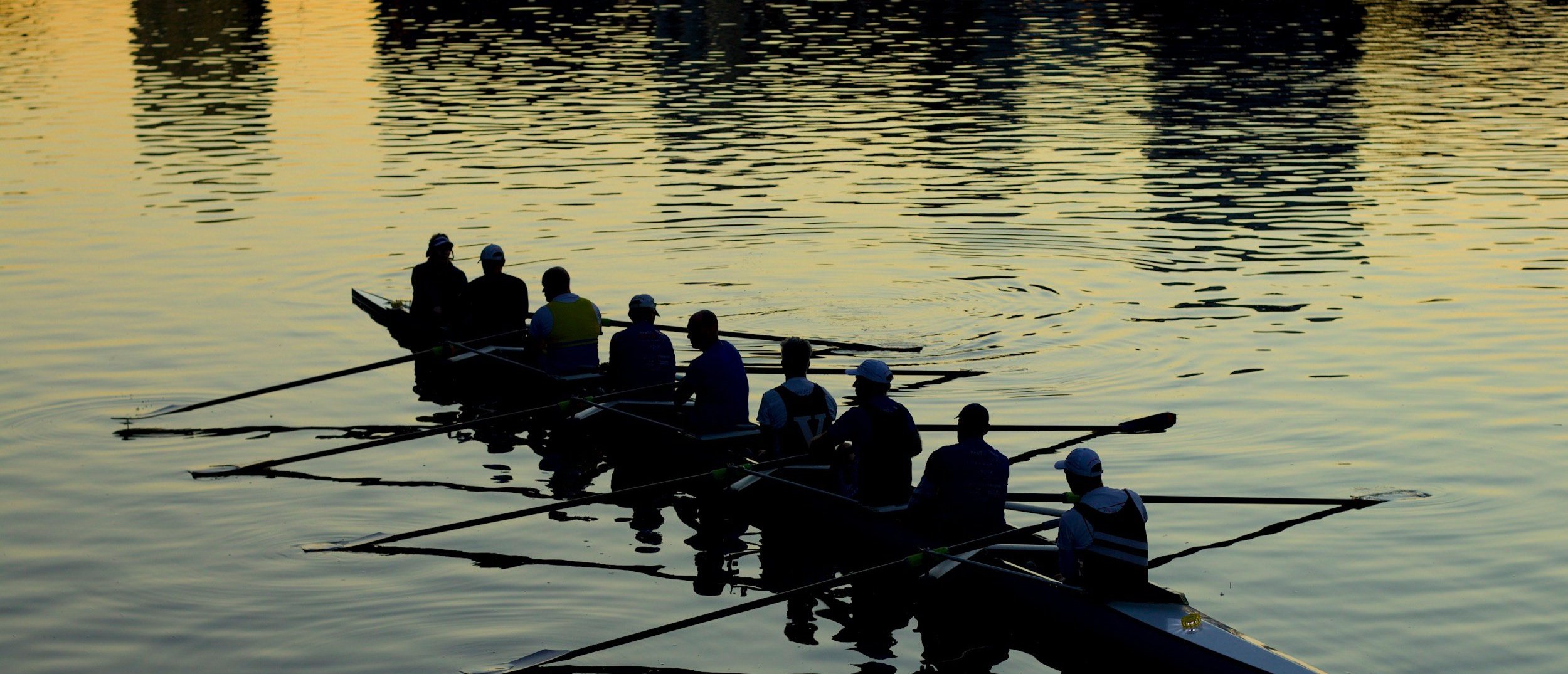 夕暮れ時の湖でボートに乗る複数の人々