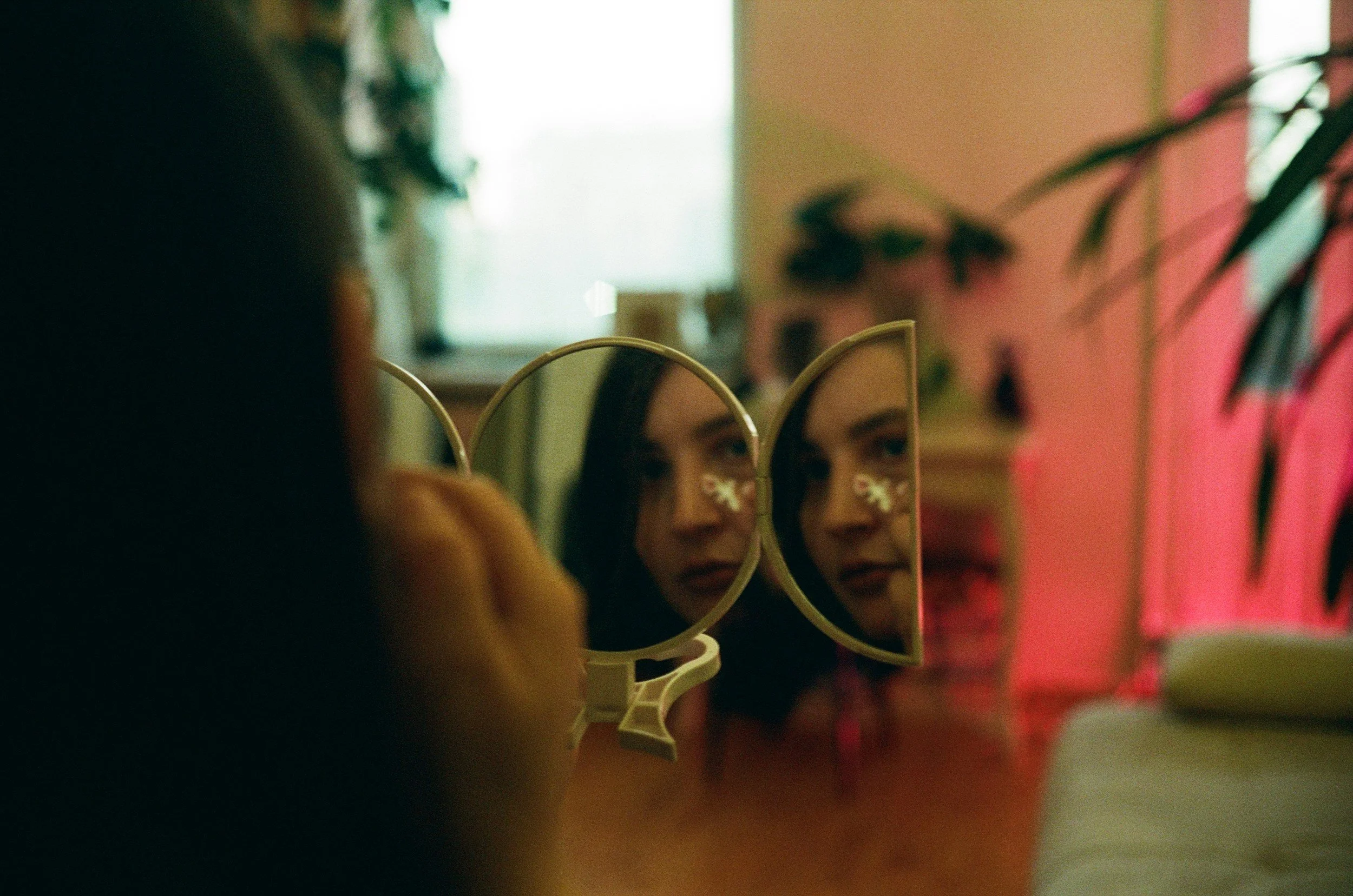 and image of a woman looking into 3 mirrors