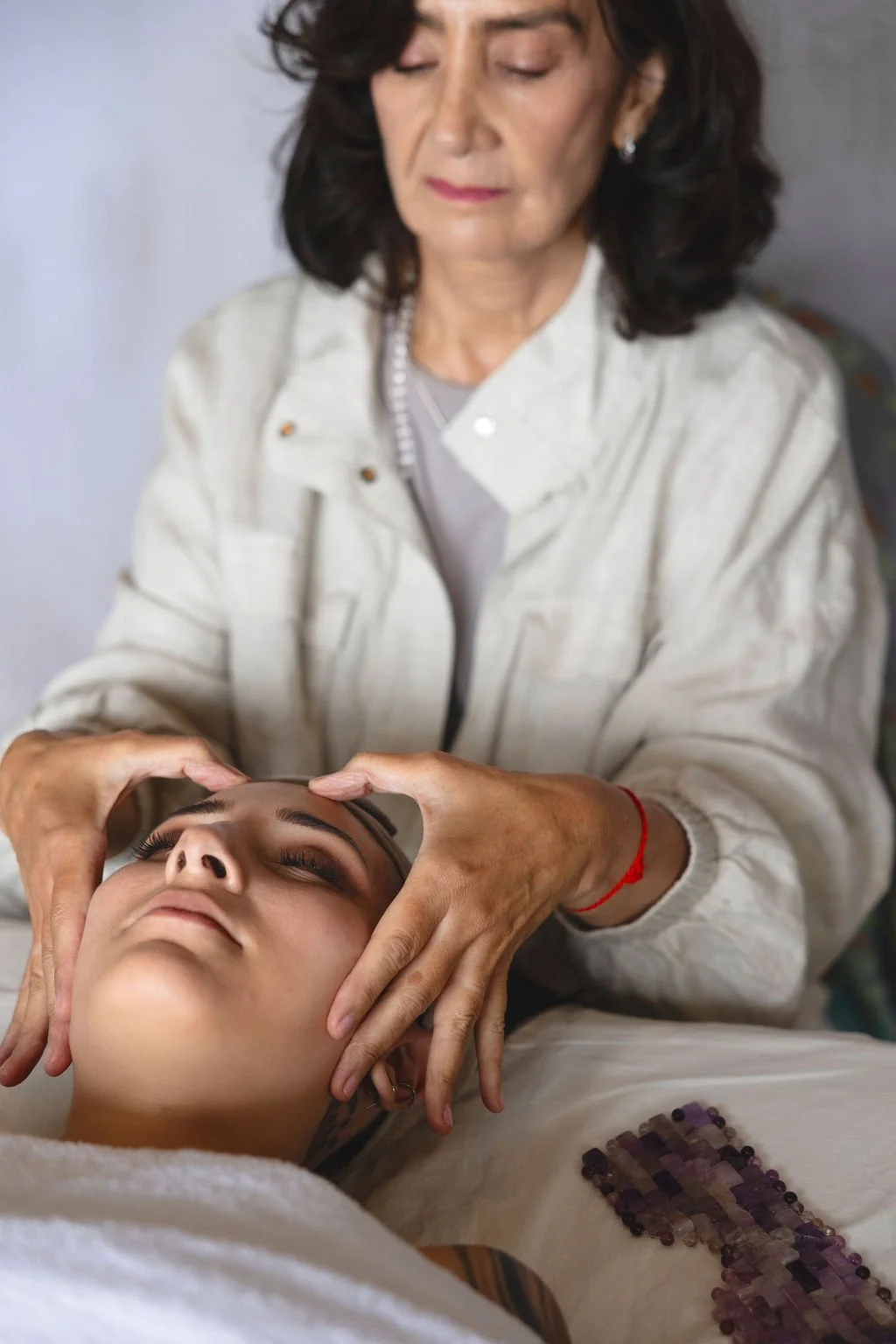 A woman getting a facial massage from an esthetician in a spa or beauty clinic setting.