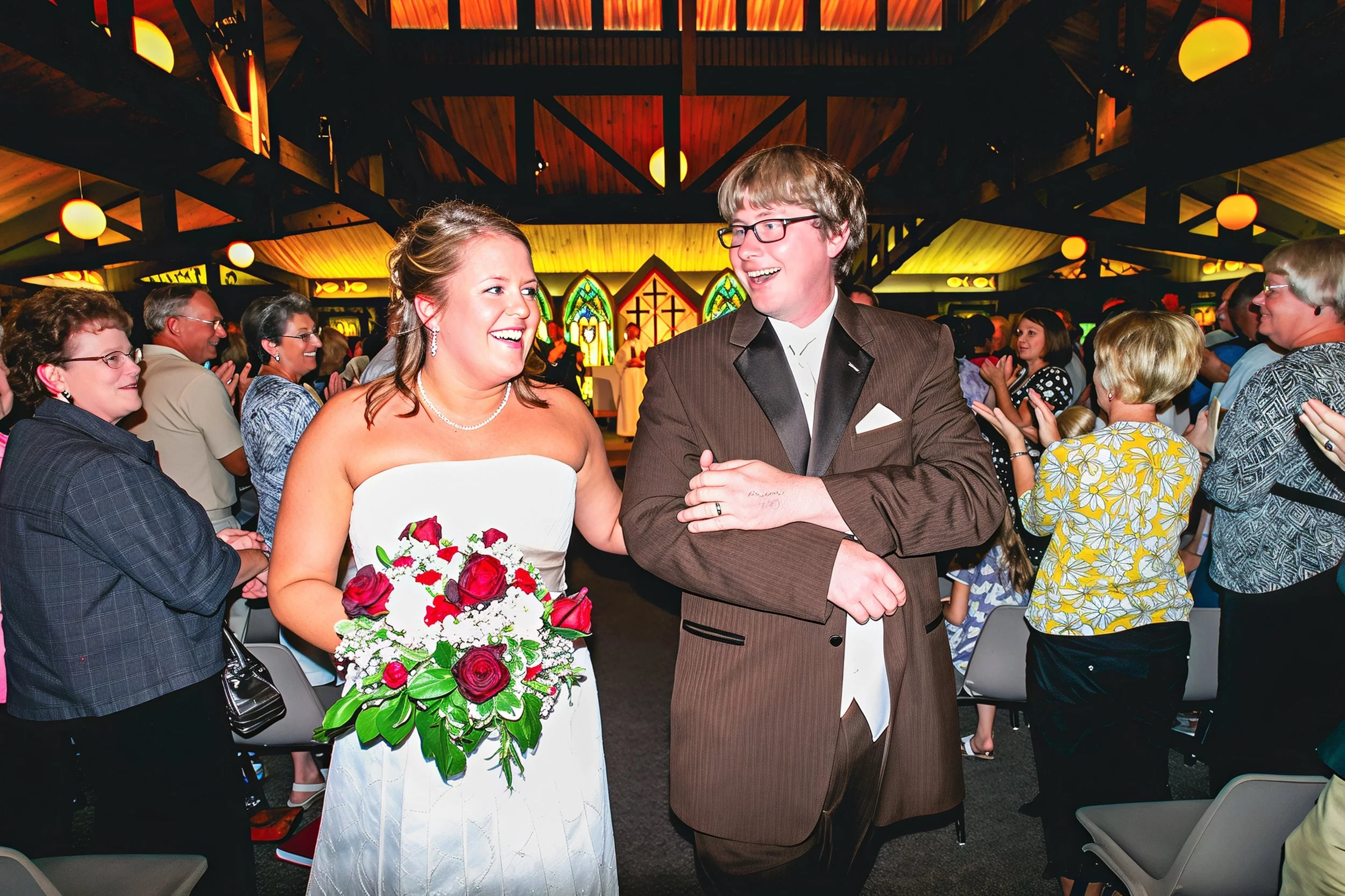 A bride and groom walking down the aisle during their wedding ceremony, smiling and looking at each other, surrounded by guests in a church with stained glass windows and warm lighting.