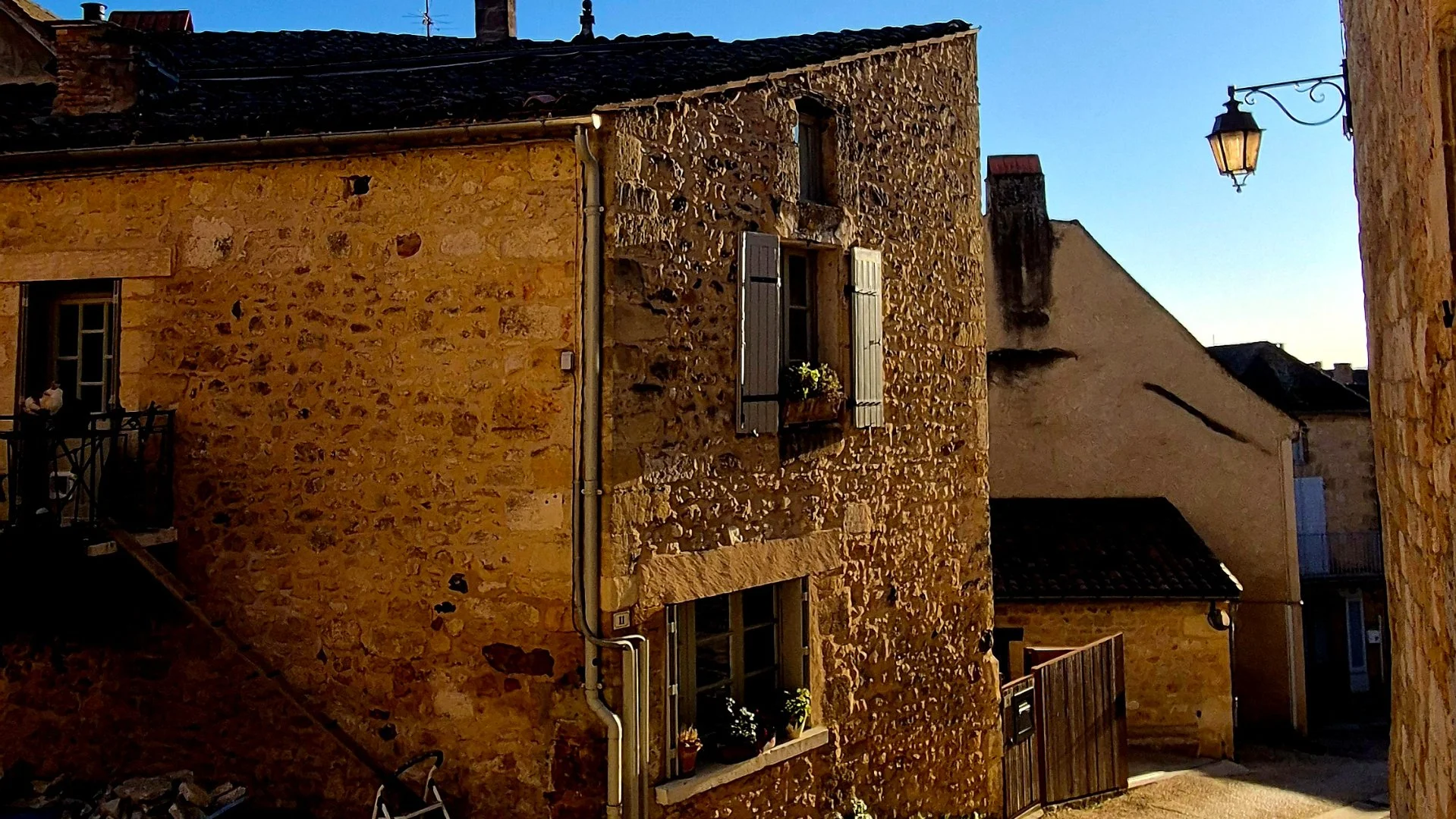 Street view in st cyprien Dordogne with honey coloured stone and sun glistening off the stone.
