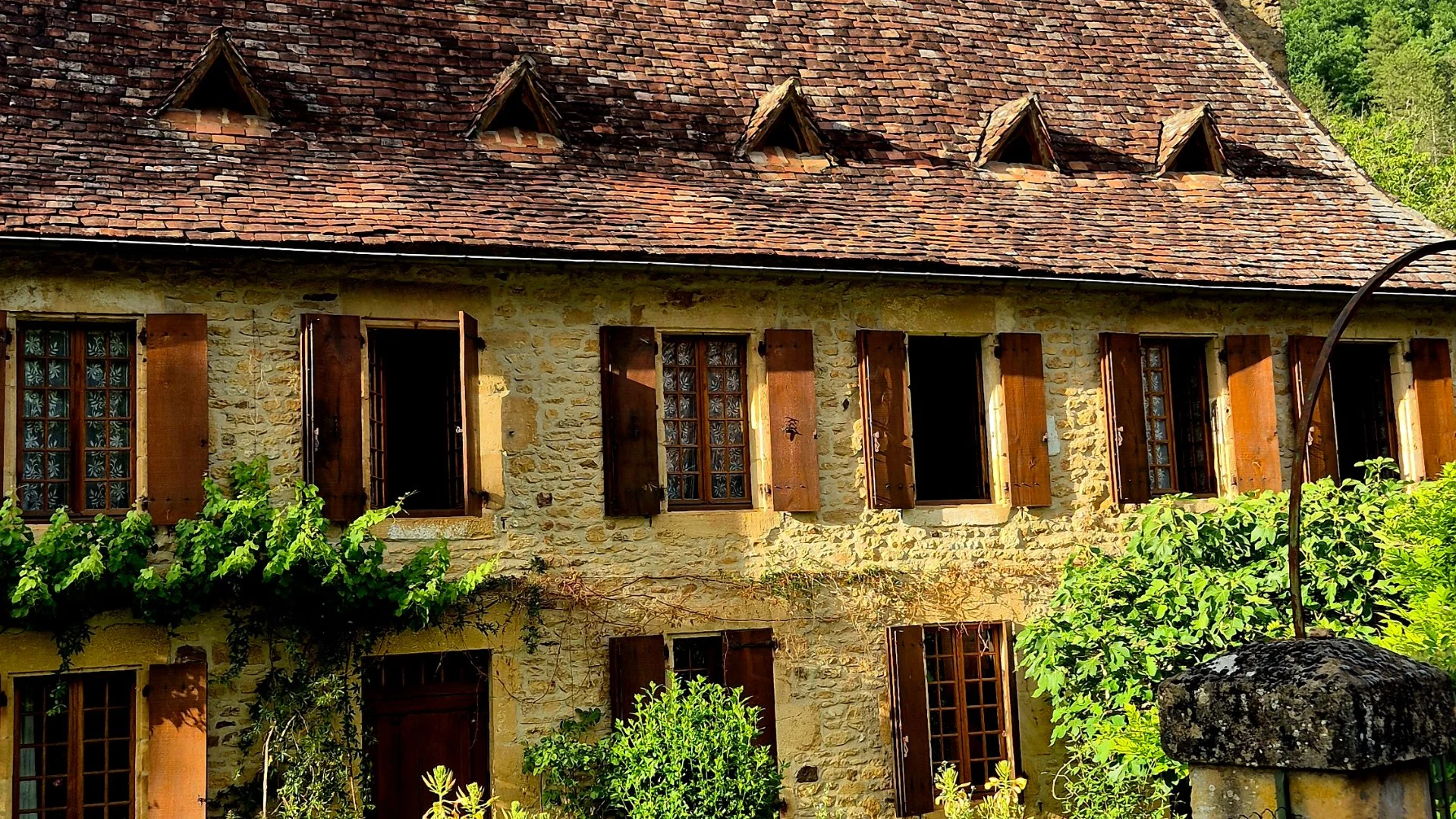 Old property in Urval Dordogne with stunning roof and lovely brown shutters.