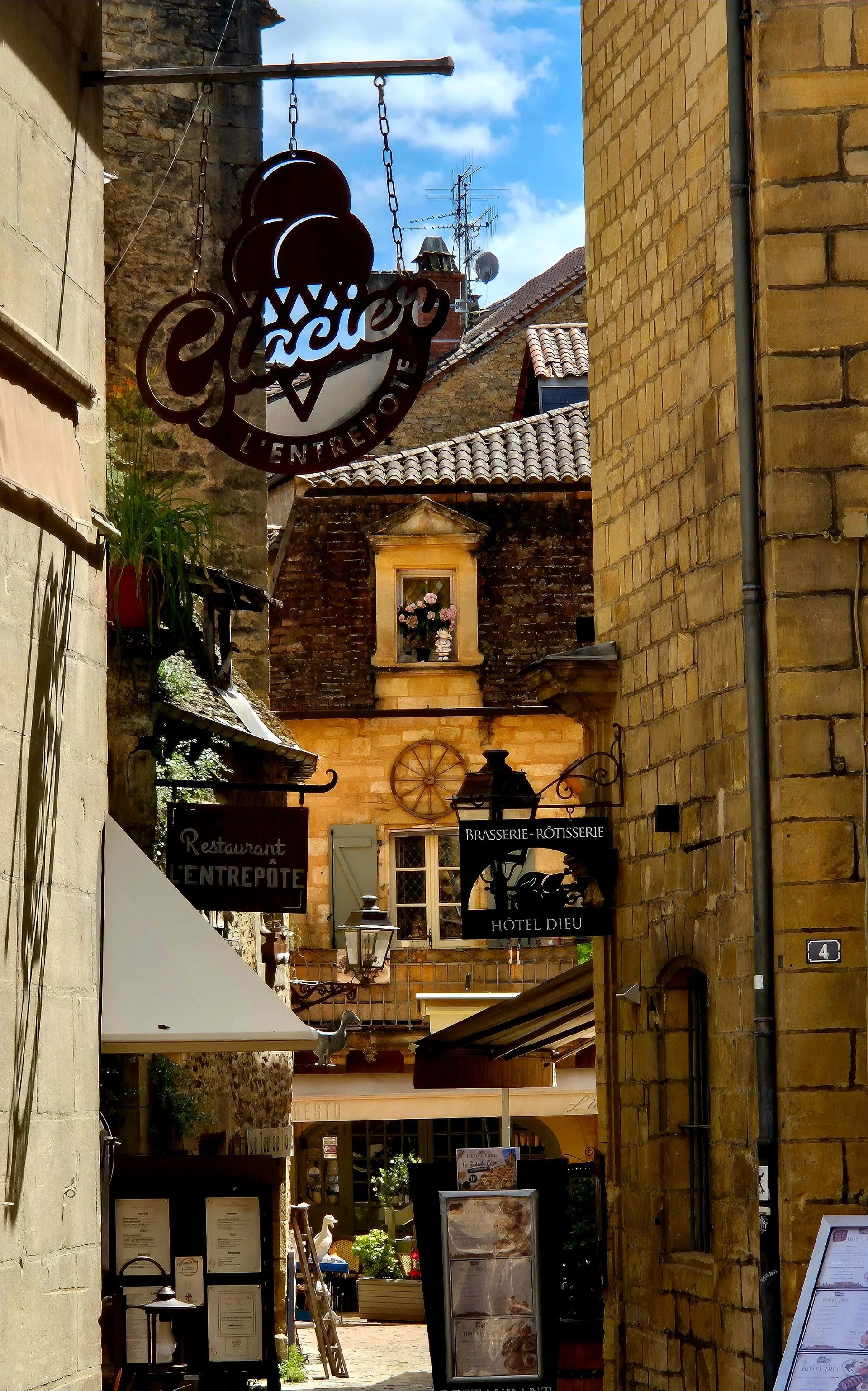Medieval street in Sarlat with honey coloured buildings and hanging street signs