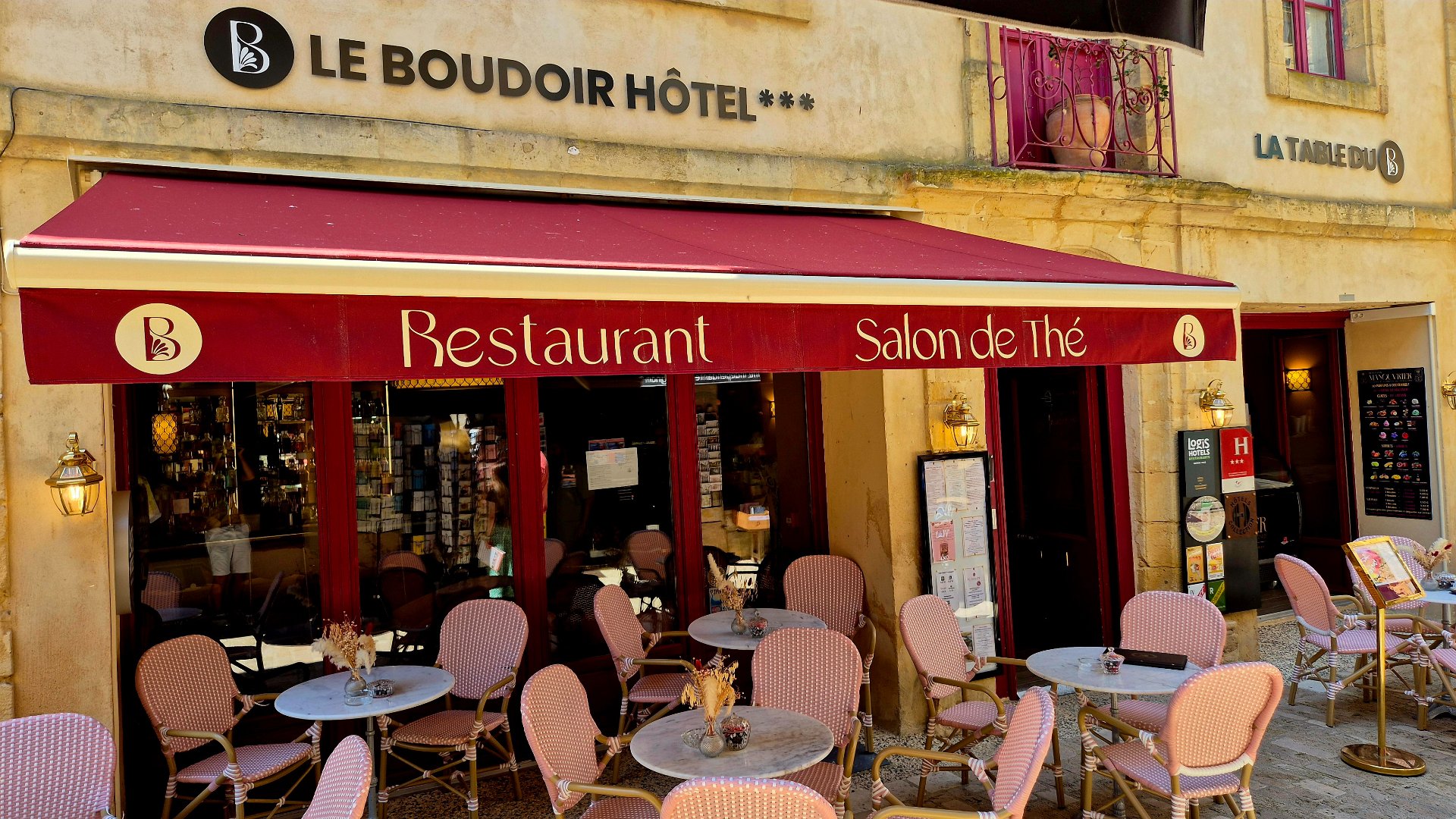 Le boudoir hotel, bar and restaurant withe a red canopy and beautiful pink chairs surrounding cafe style chairs