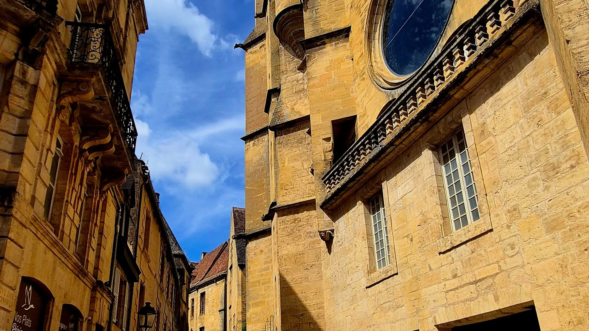 A statue of a medieval knight holding a shield, mounted on a stone wall outside a restaurant called Le Moulin des Chevaliers in Sarlat, Dordogne