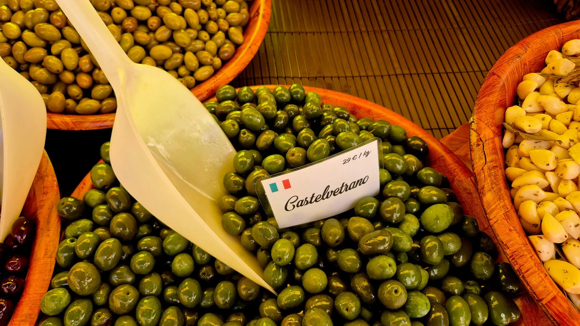 A picture of some castelvetrano olives in a wooden bowl at la pomponette olive stall at belves market