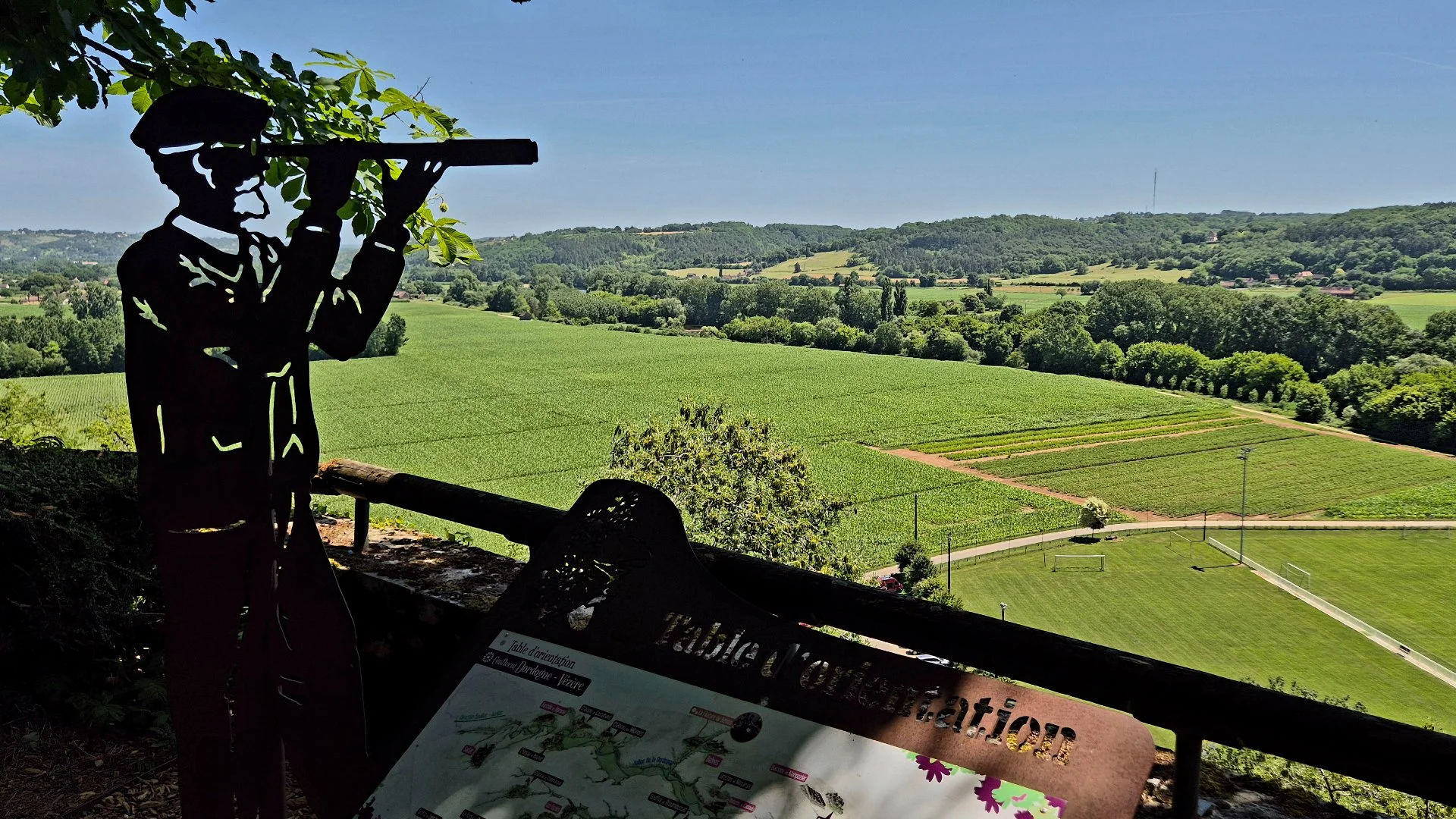 A view over the fields of Limeuil from the gardens with a metal sculpture of a man with a telescope looking at the view of green fields