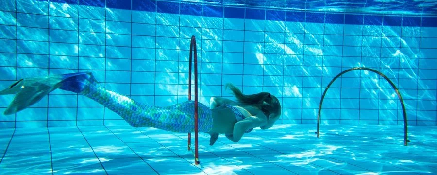 Meisje in een zwembad zwemt door een inductiebeetje tijdens een watergevecht.
