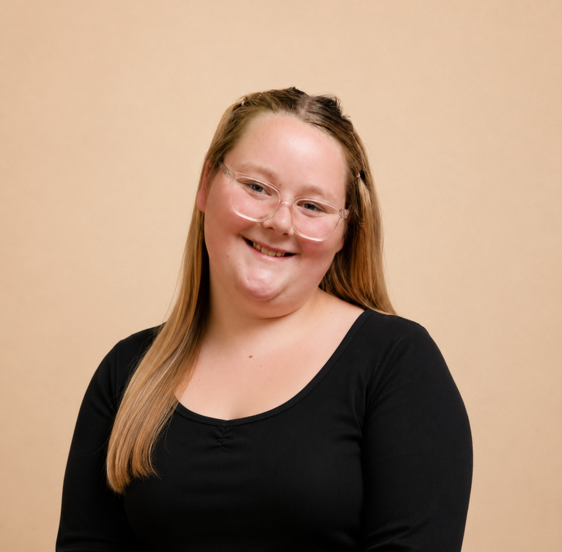 Een lachende vrouw met lang blond haar, draagt een zwarte top en bril, tegen een beige achtergrond.