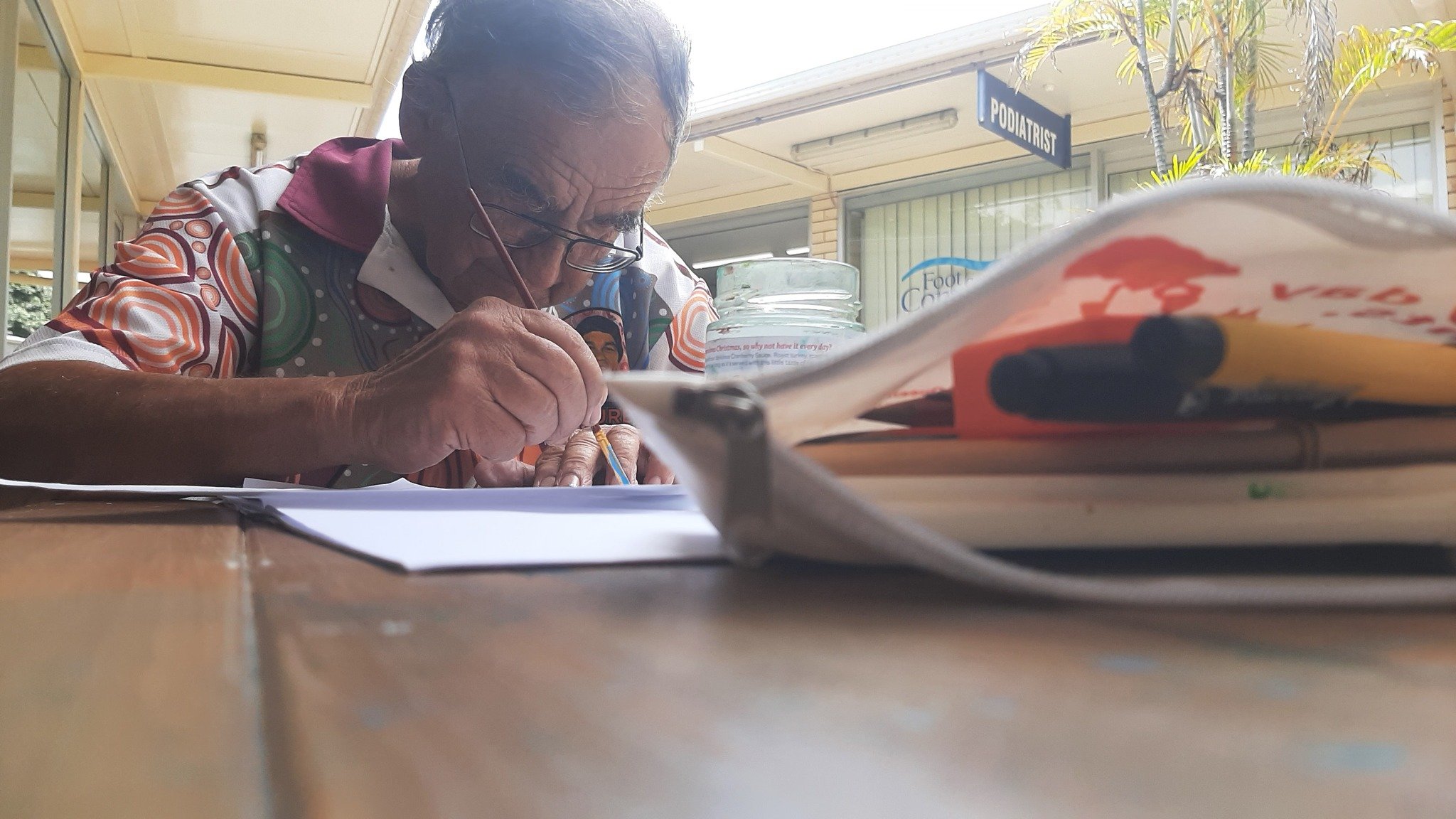 Two hands exchanging a black paper heart against a plain white background.