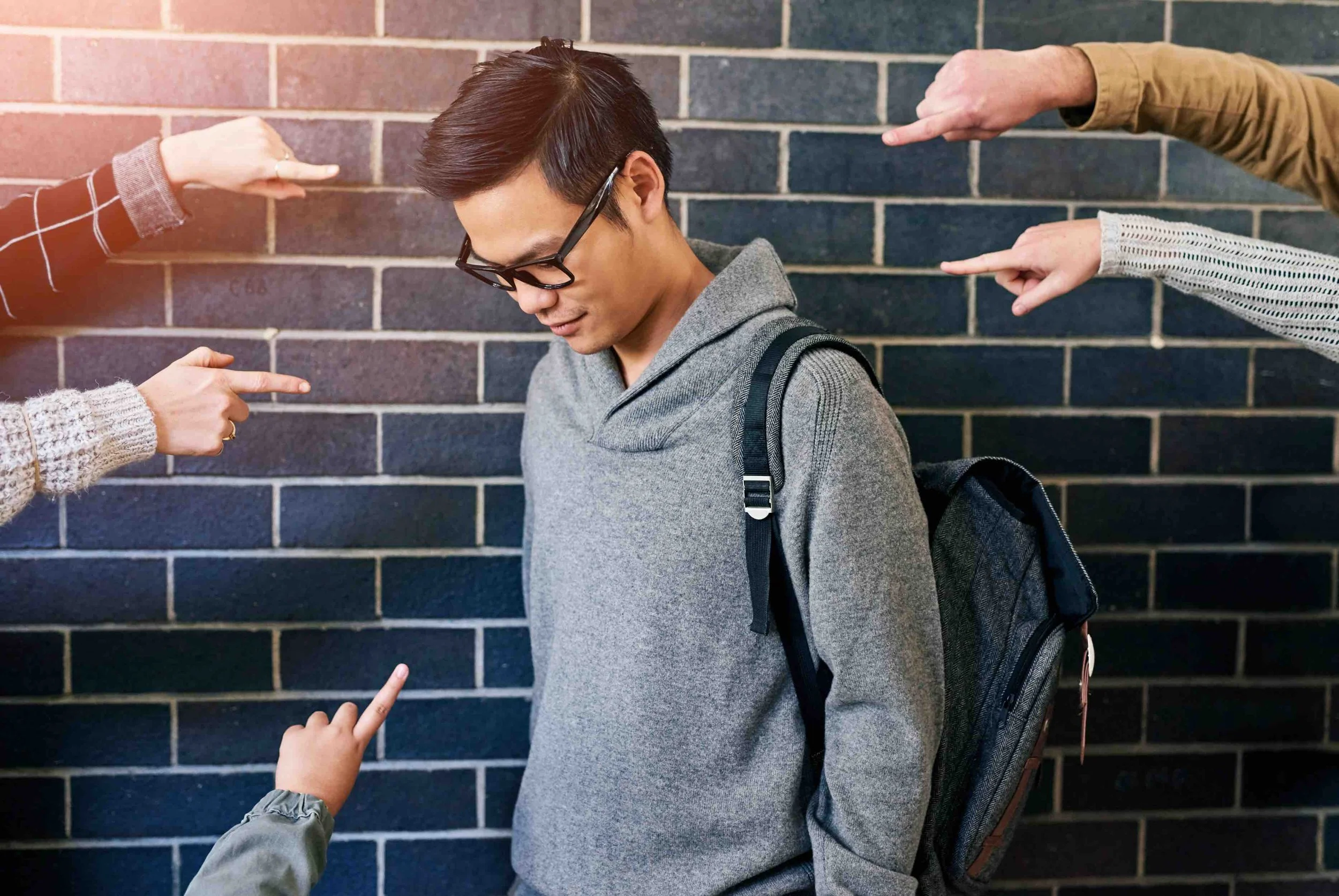 Sunnyside is against bullying. Teenager with glasses carrying a backpack being bullied