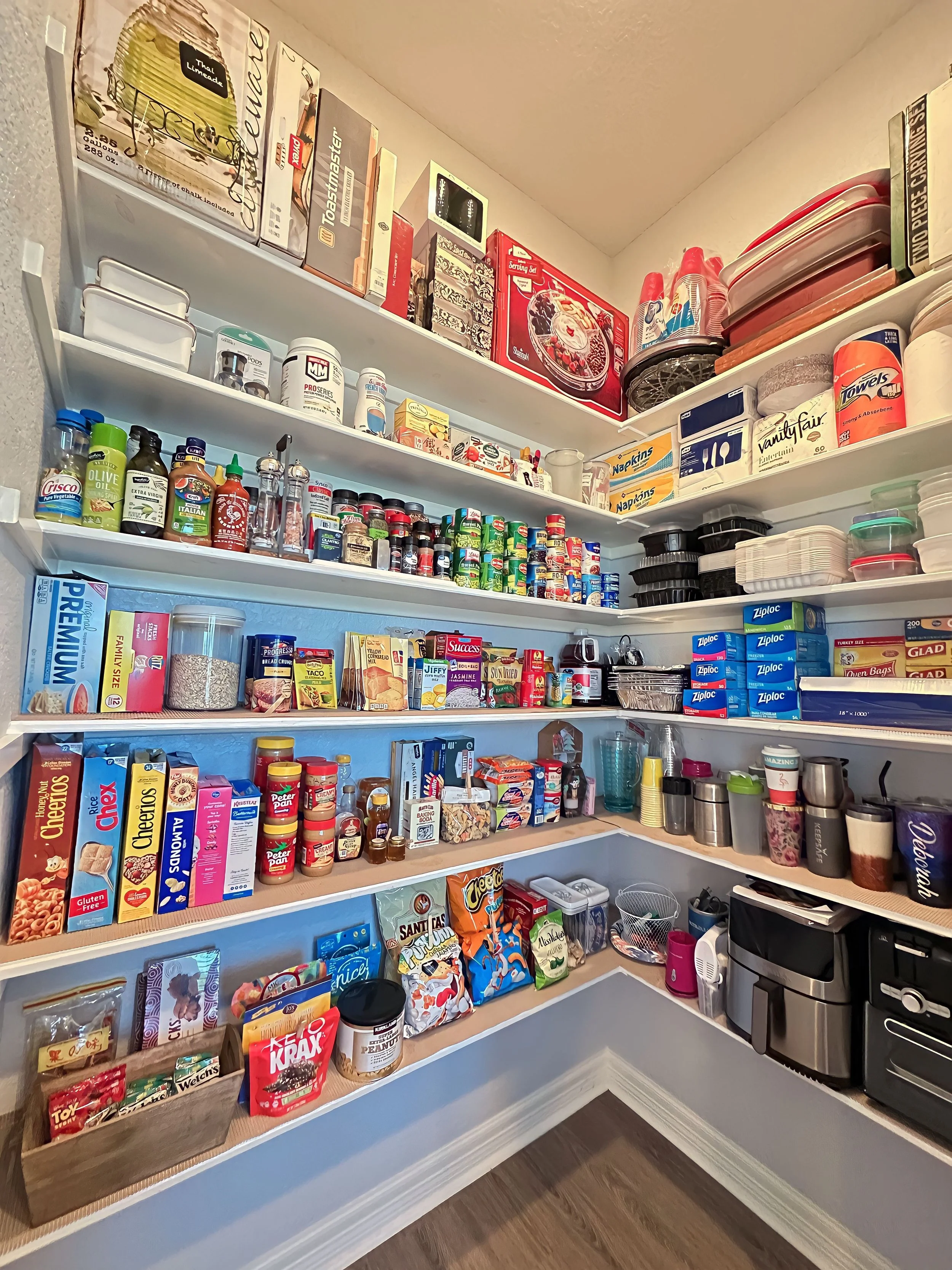 Pantry with shelves filled with snacks, spices, containers, and kitchen appliances.