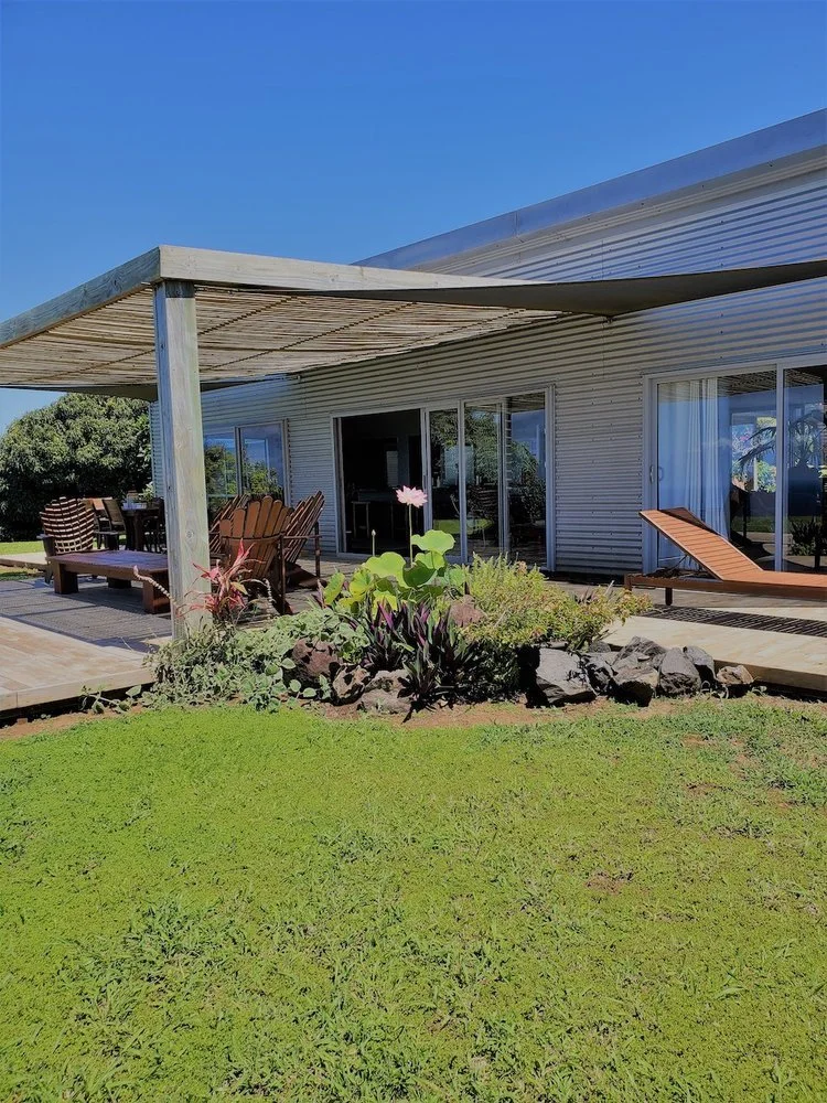 Modern patio with wooden pergola, outdoor seating, and garden in a sunny backyard.