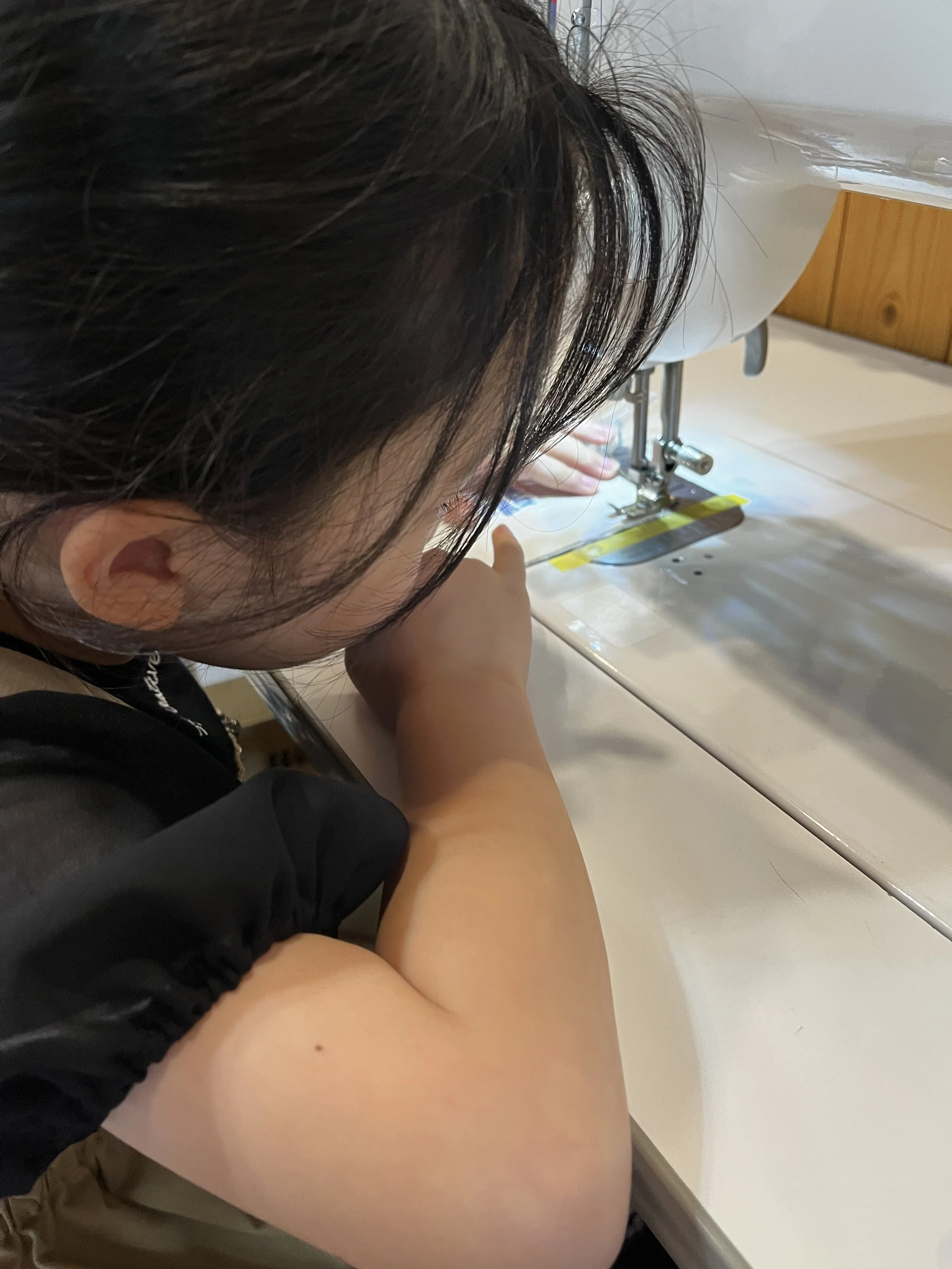 子供がミシンを使って縫い物をしている