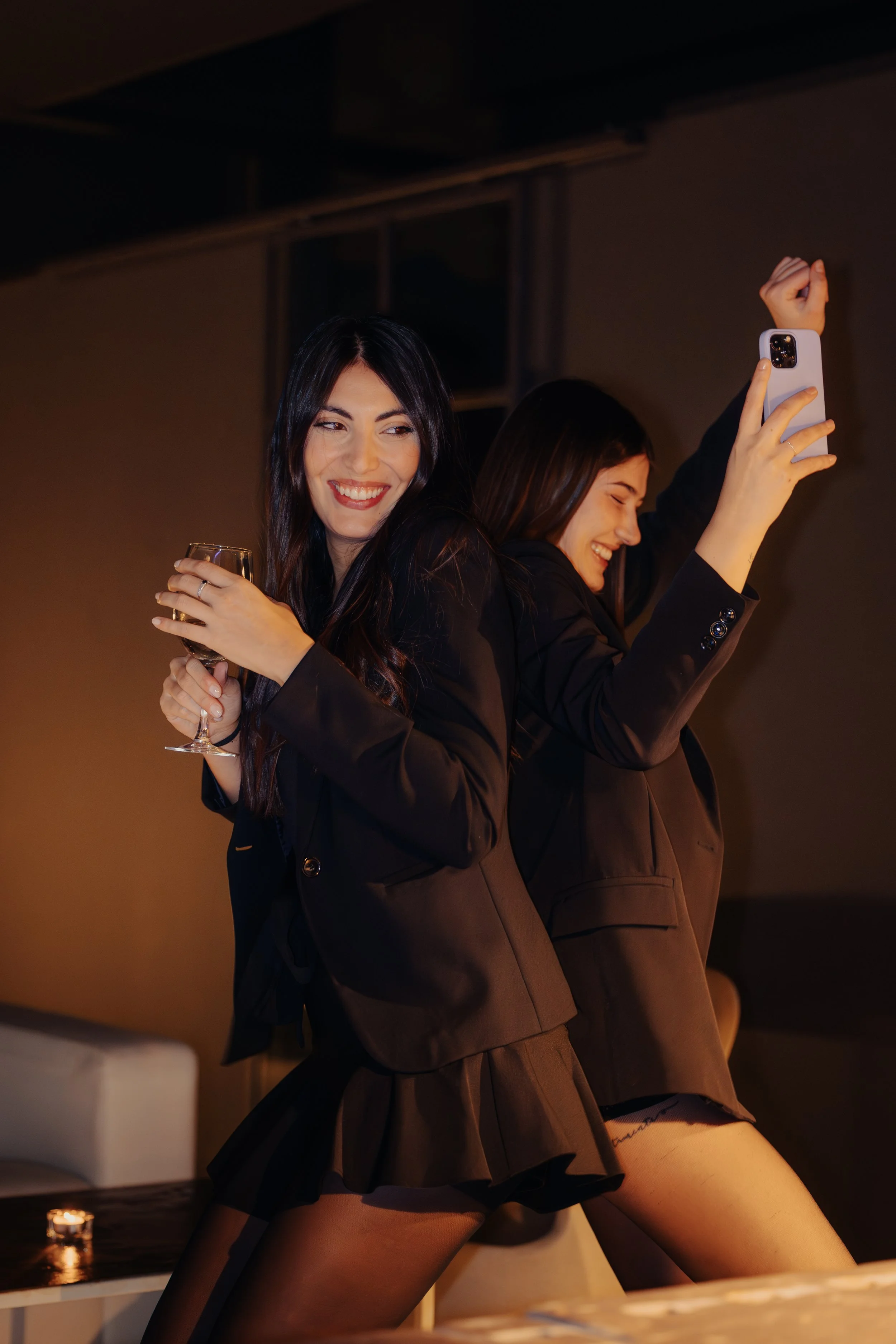 Due donne in abiti neri che si divertono e fanno foto con uno smartphone a una festa o evento.