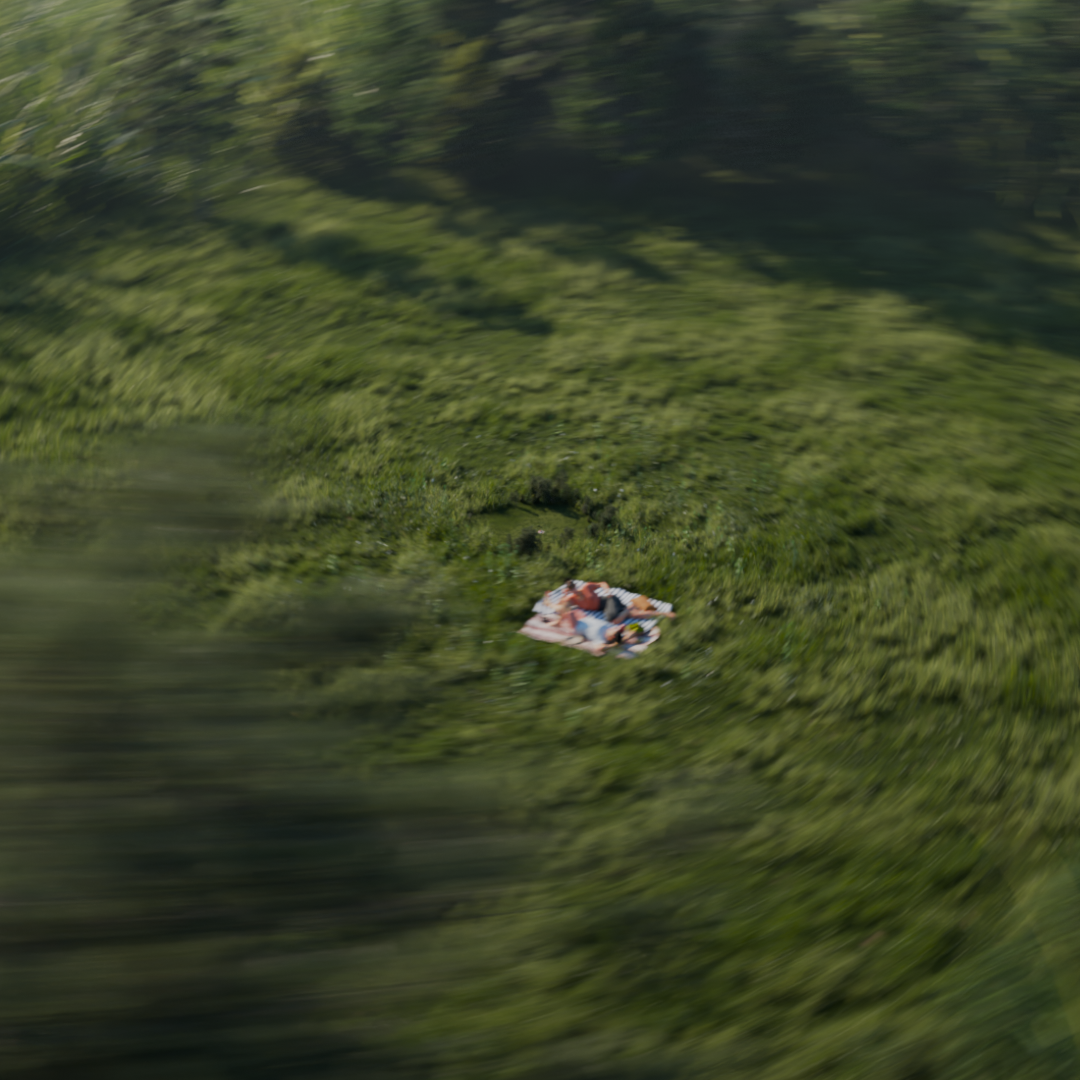 A blanket with a person lying on it in a green grassy area next to a body of water.