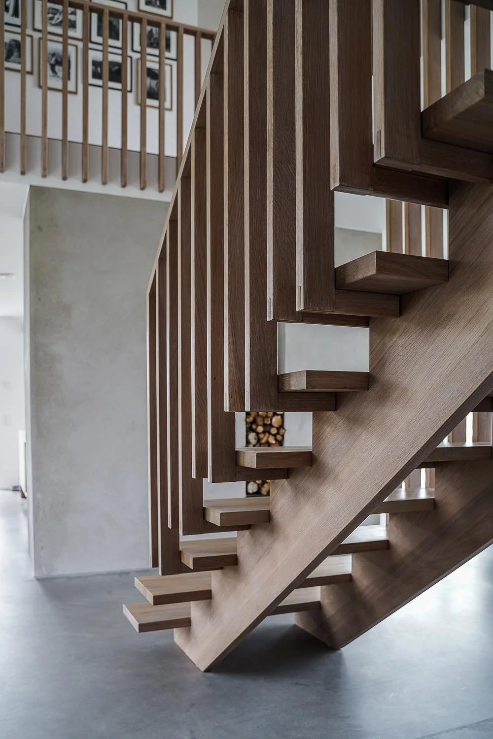 Modern trätrappa inomhus med minimalistisk design och järndetaljer i ett ljust rum med grått golv. O Lind AB.