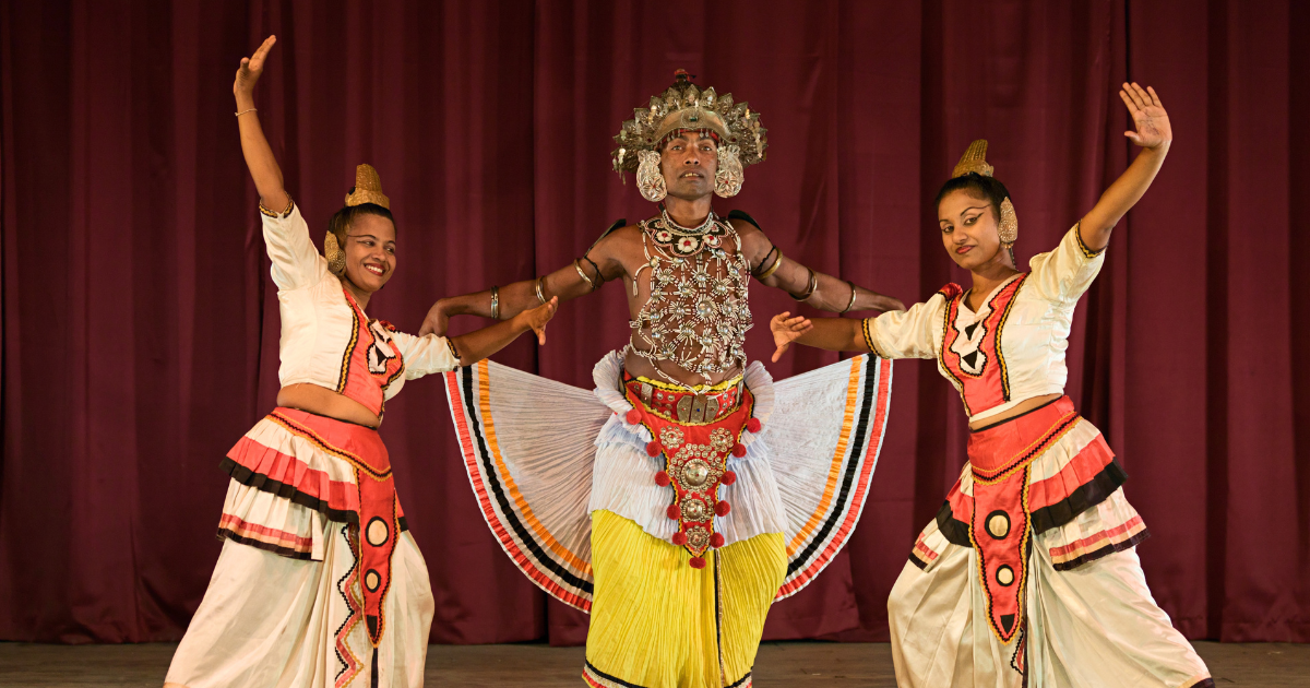 Three Kandyan dancers in traditional costume including the silver Ves headdress