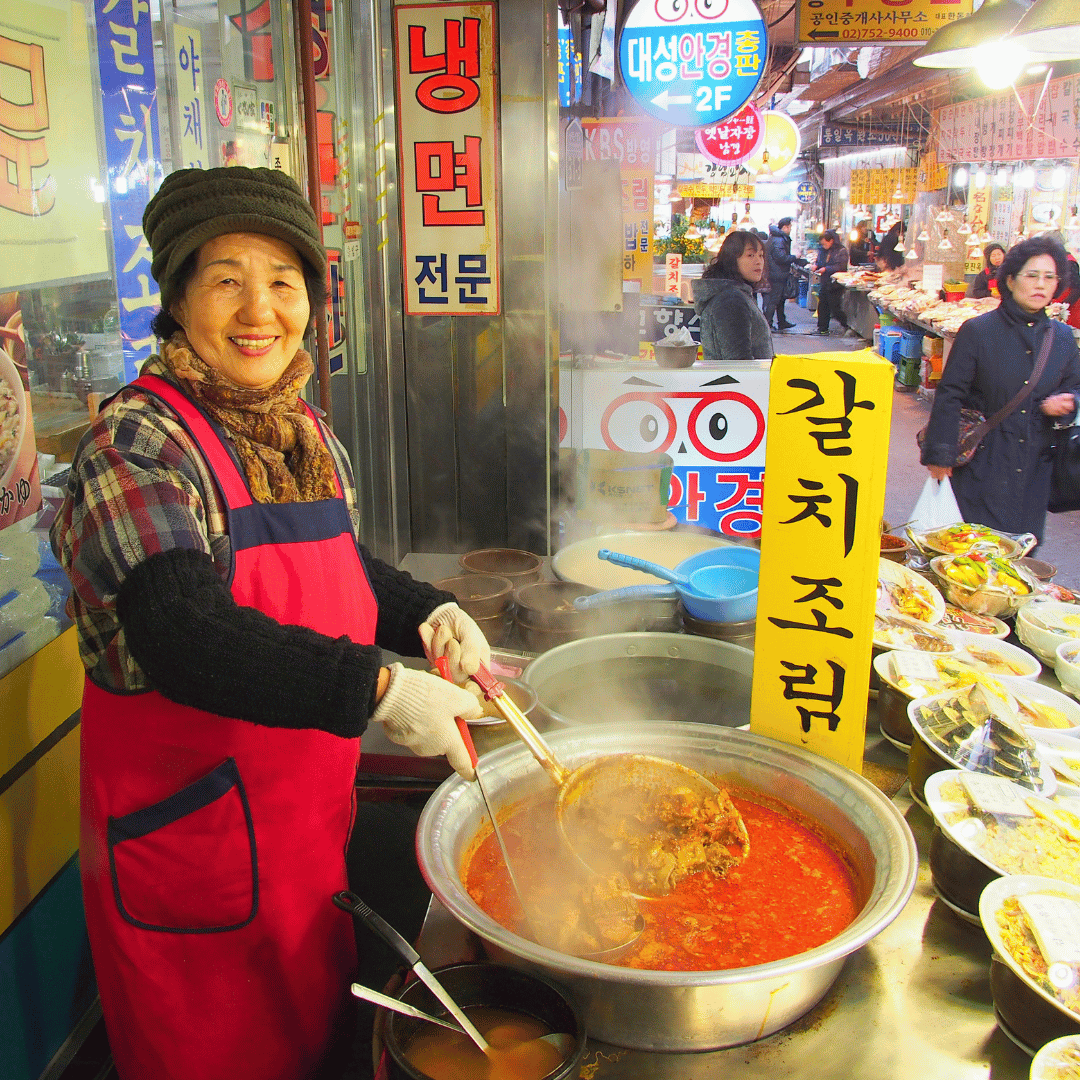 Local food vendor preparing traditional Korean dishes at Gwangjang Market in Seoul.