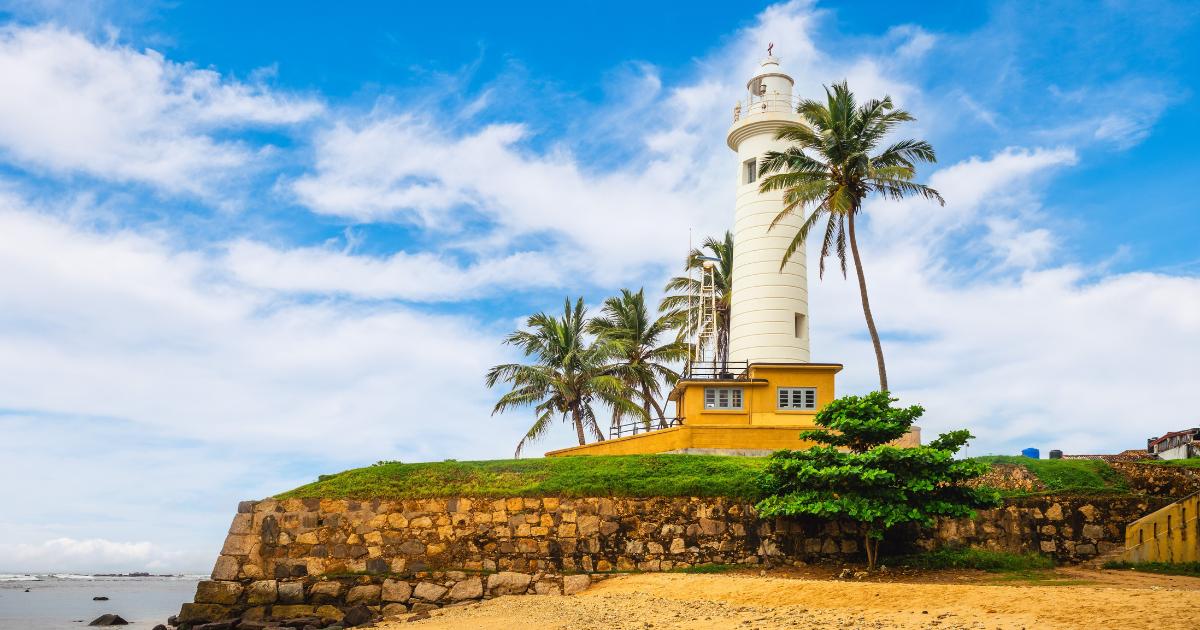 The Galle Lighthouse on the Utrecht Bastion surrounded by palm trees with the Indian Ocean behind