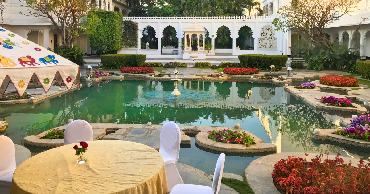 Outdoor dining table set beside an ornamental water courtyard at a heritage hotel in Udaipur