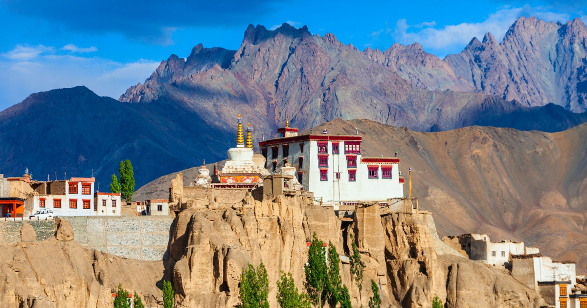 Lamayuru Monastery perched on eroded sandstone cliffs in Ladakh with jagged mountain peaks behind.