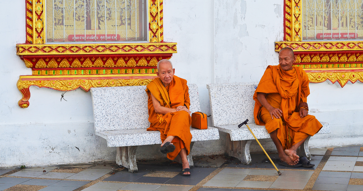 Two Buddhist monks resting on benches outside a building at Wat Phra That Doi Suthep