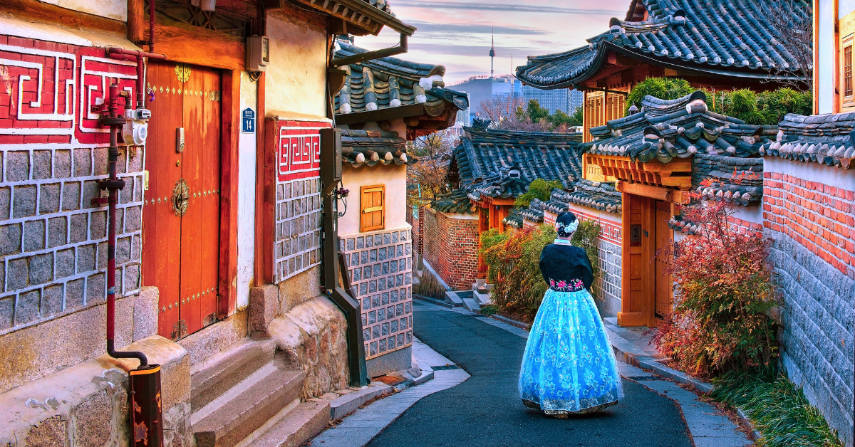 Visitor wearing a traditional hanbok walking through Bukchon Hanok Village in Seoul, South Korea.