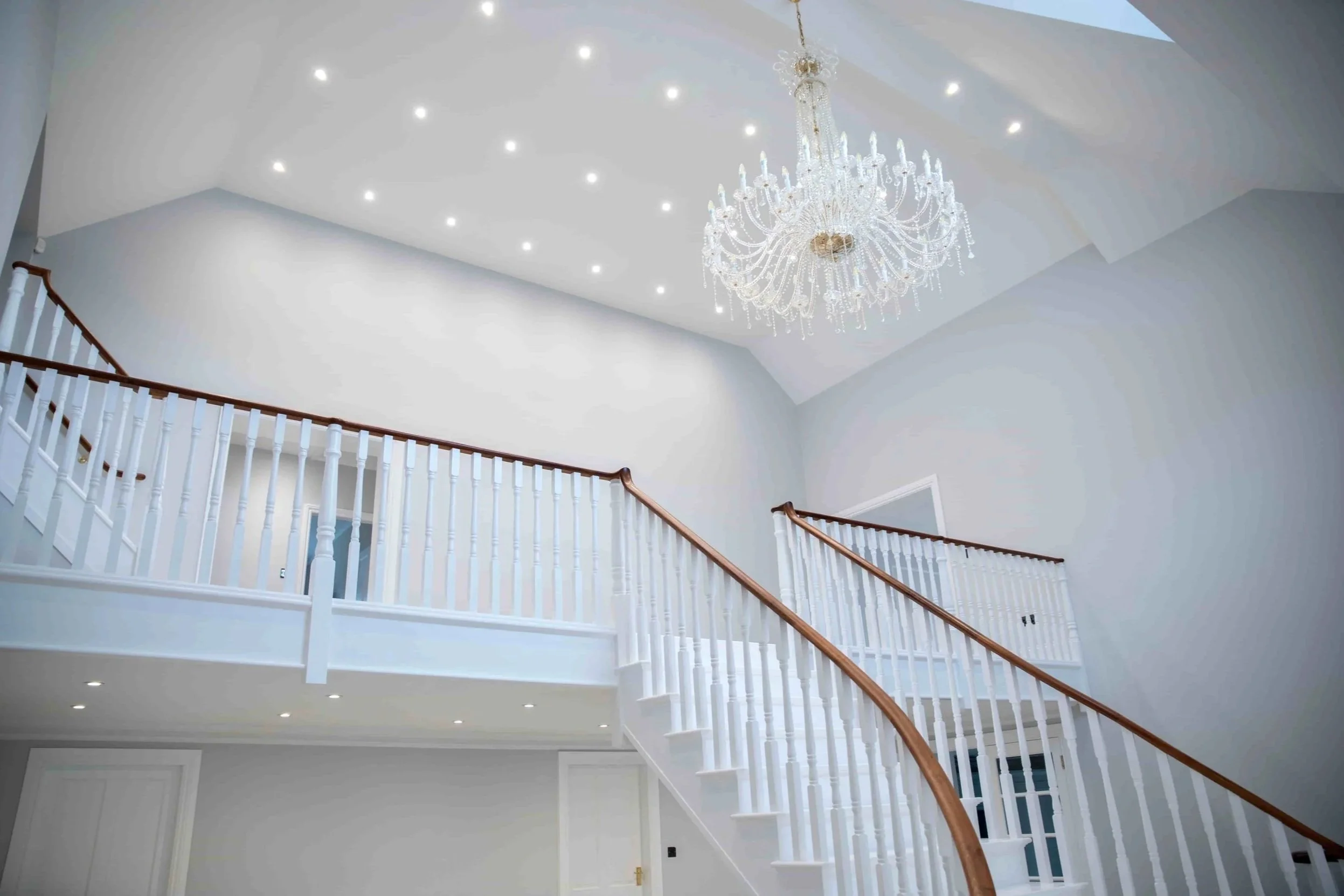 Grand entrance hall featuring a bespoke staircase, vaulted ceiling, crystal chandelier and high-end residential finishes.