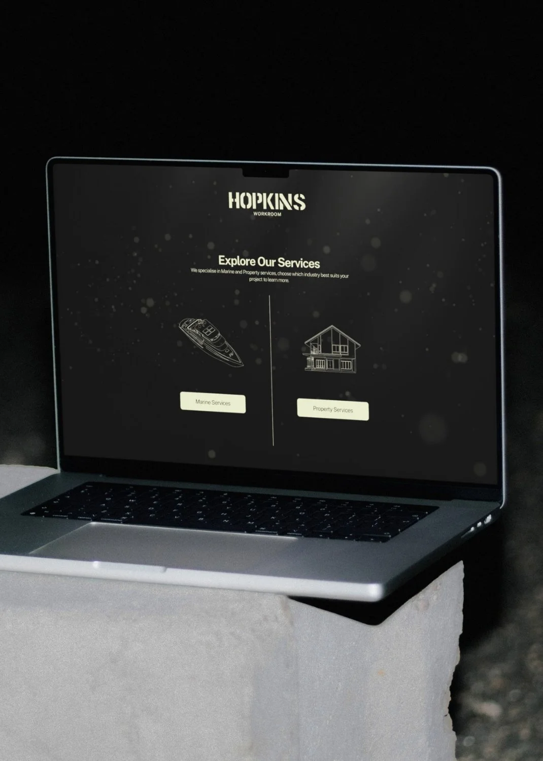 Laptop displaying a webpage titled 'Hopkins Workroom' with options for 'Marine Services' and 'Property Services'.