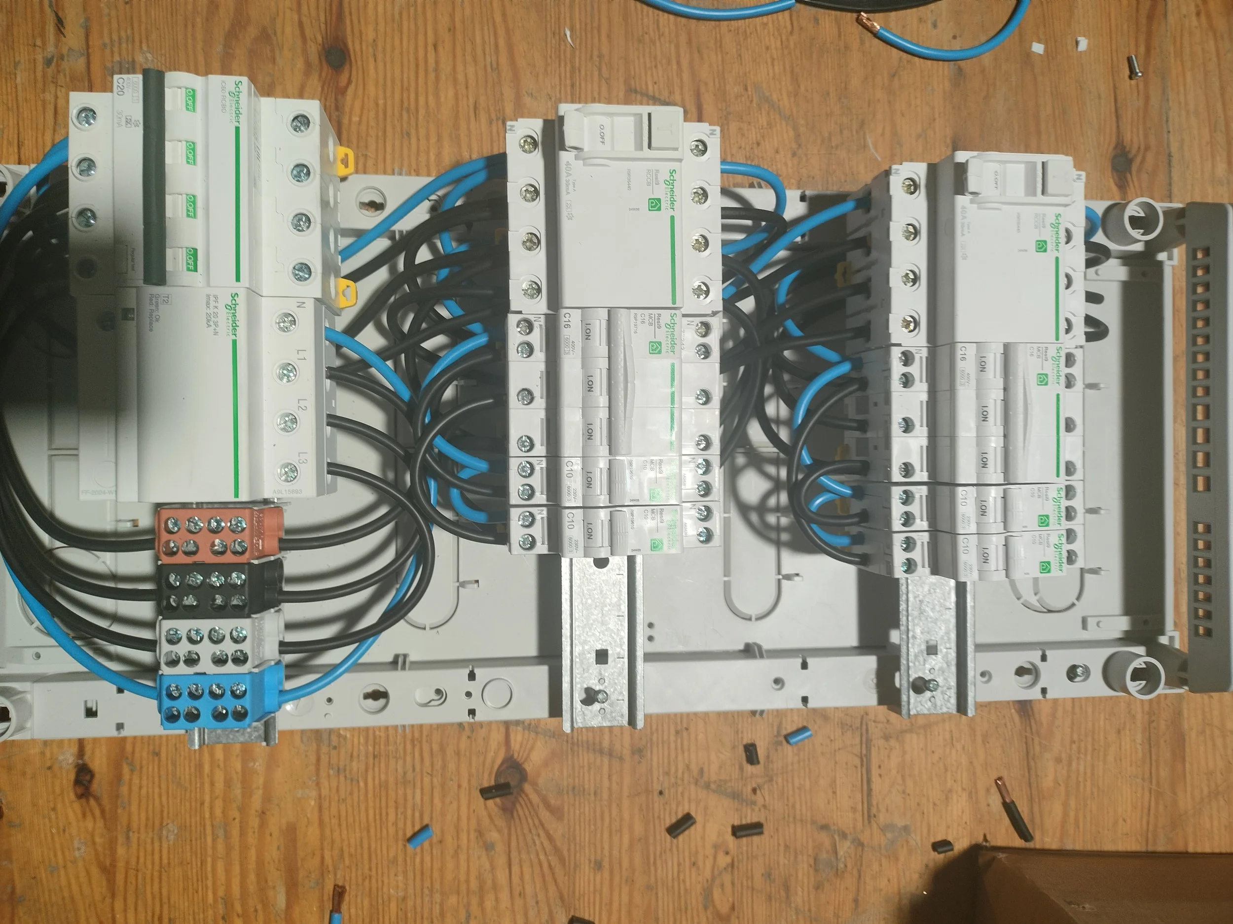 Elektrisk installation med flere kontaktorer og ledninger installeret på en træbordplade.